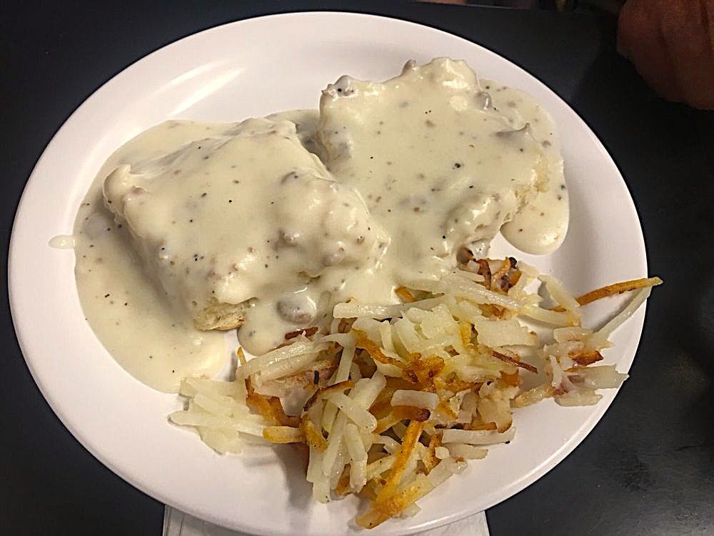 Plate of biscuits and gravy with hash browns on a white dish