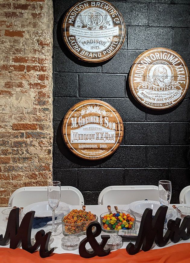 Rustic wall with beer signs above a table set for a dessert or event display