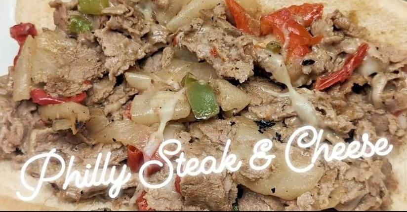 Philly steak and cheese sandwich with melted cheese, peppers, and onions in close-up