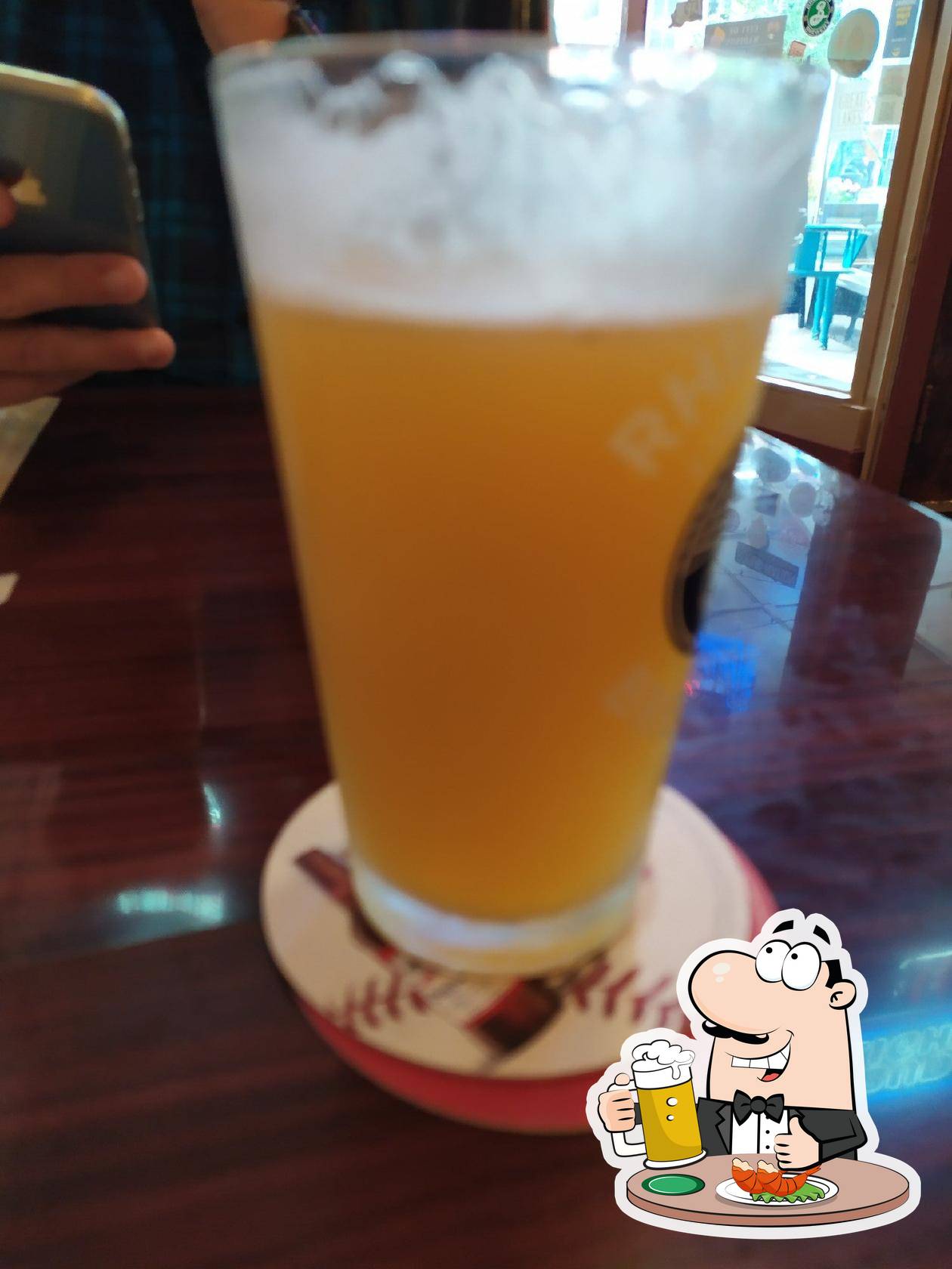 A glass of beer sits on a coaster on a table