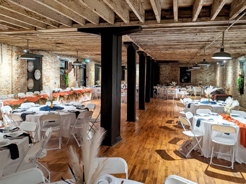A large room with tables and chairs set up for a wedding reception.