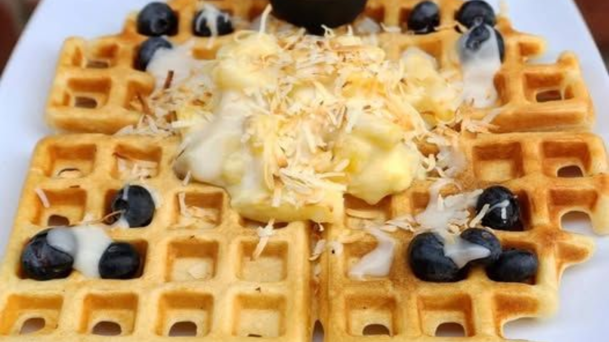 Waffle topped with blueberries, whipped cream, and shredded cheese on a plate