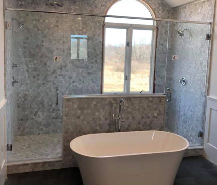 A bathroom with a tub , shower , and window.