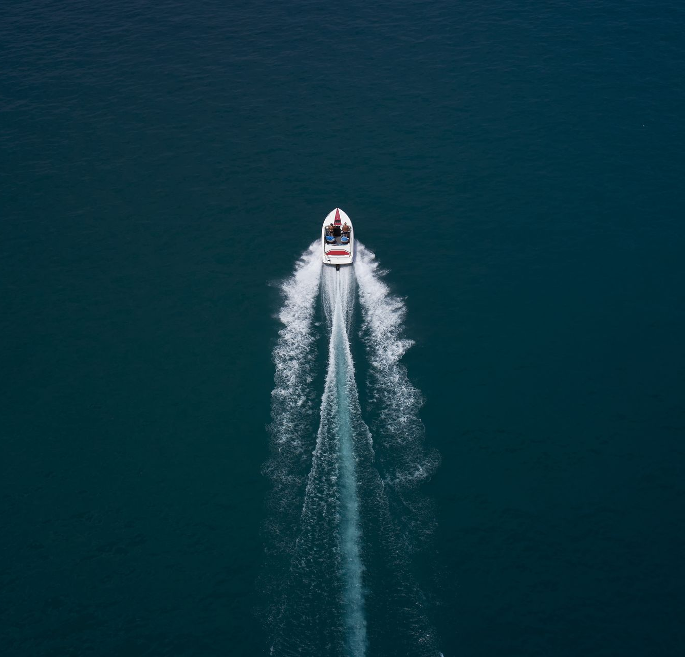 Boat speeding across dark blue water, leaving a white wake trail.