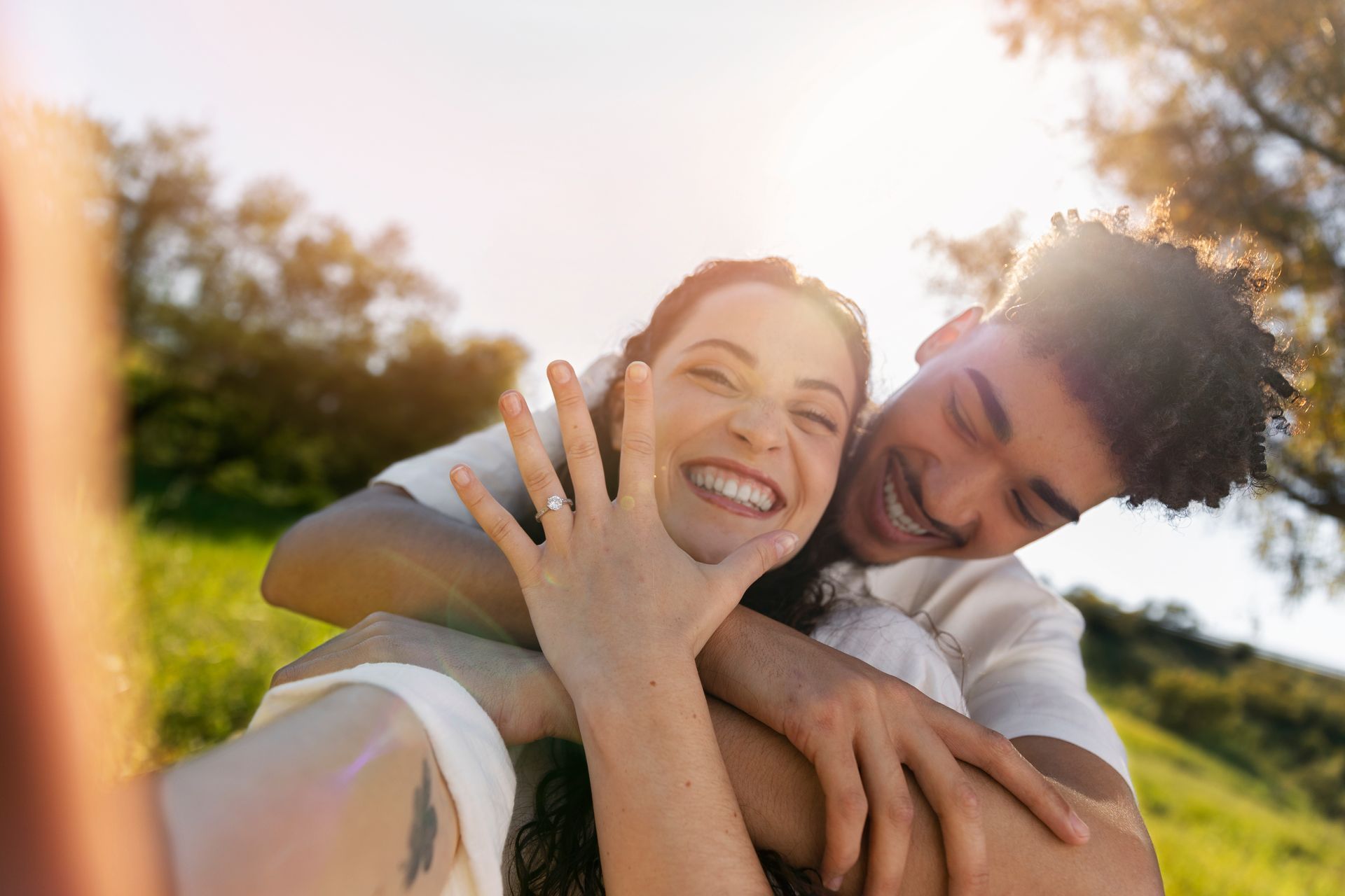 A man is giving a woman a piggyback ride in a park. 