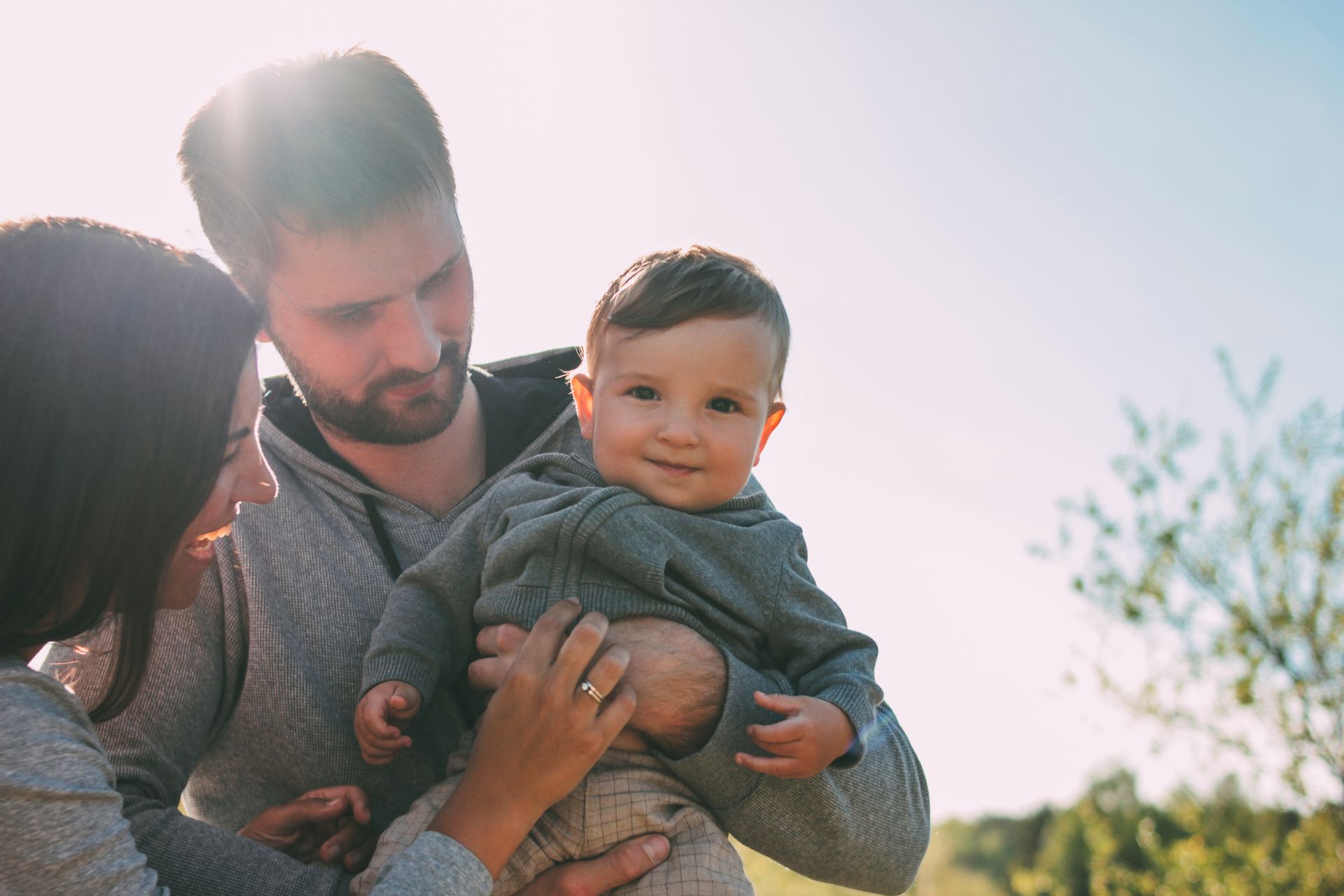 A man and woman are holding a baby in their arms. 