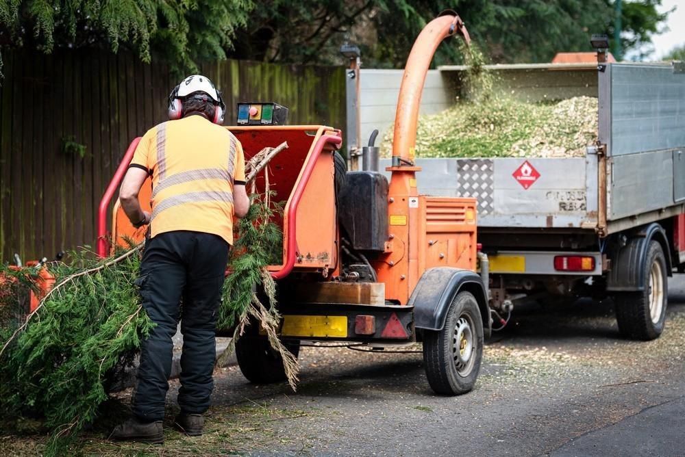 a man is working on a tree chipper next to a truck .
