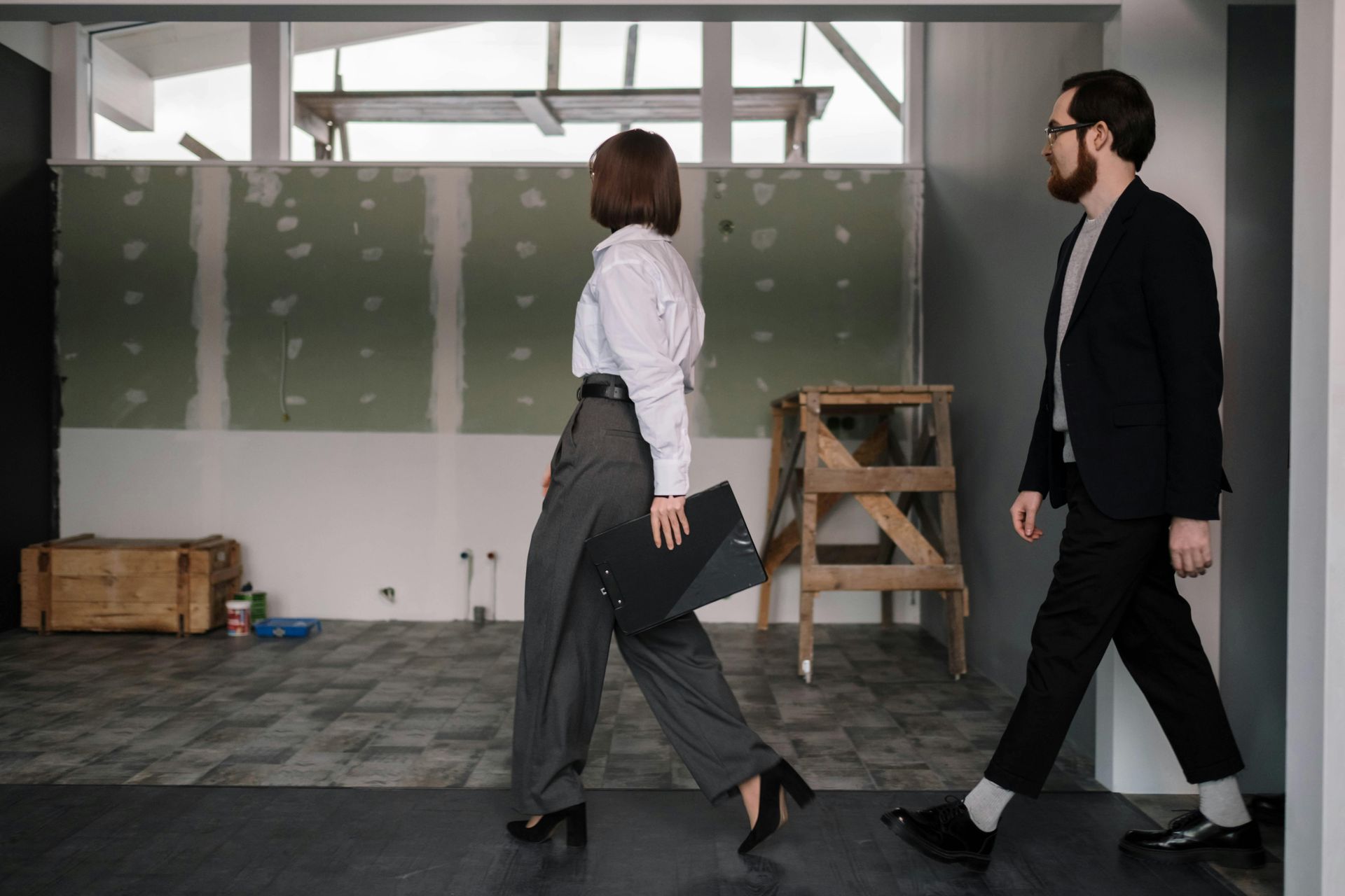 A man and a woman are walking through an empty room.