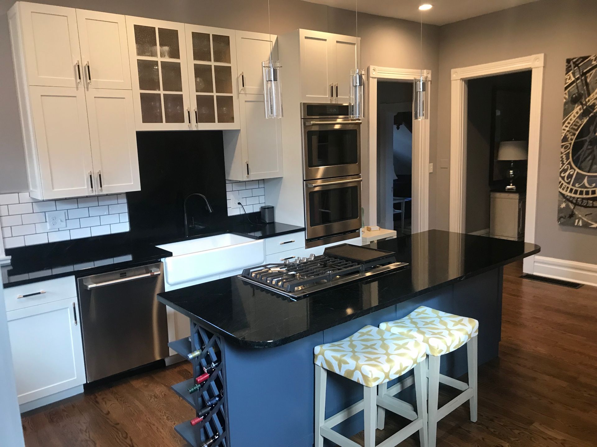 Modern kitchen with white cabinets, black countertops, and a blue island with seating.