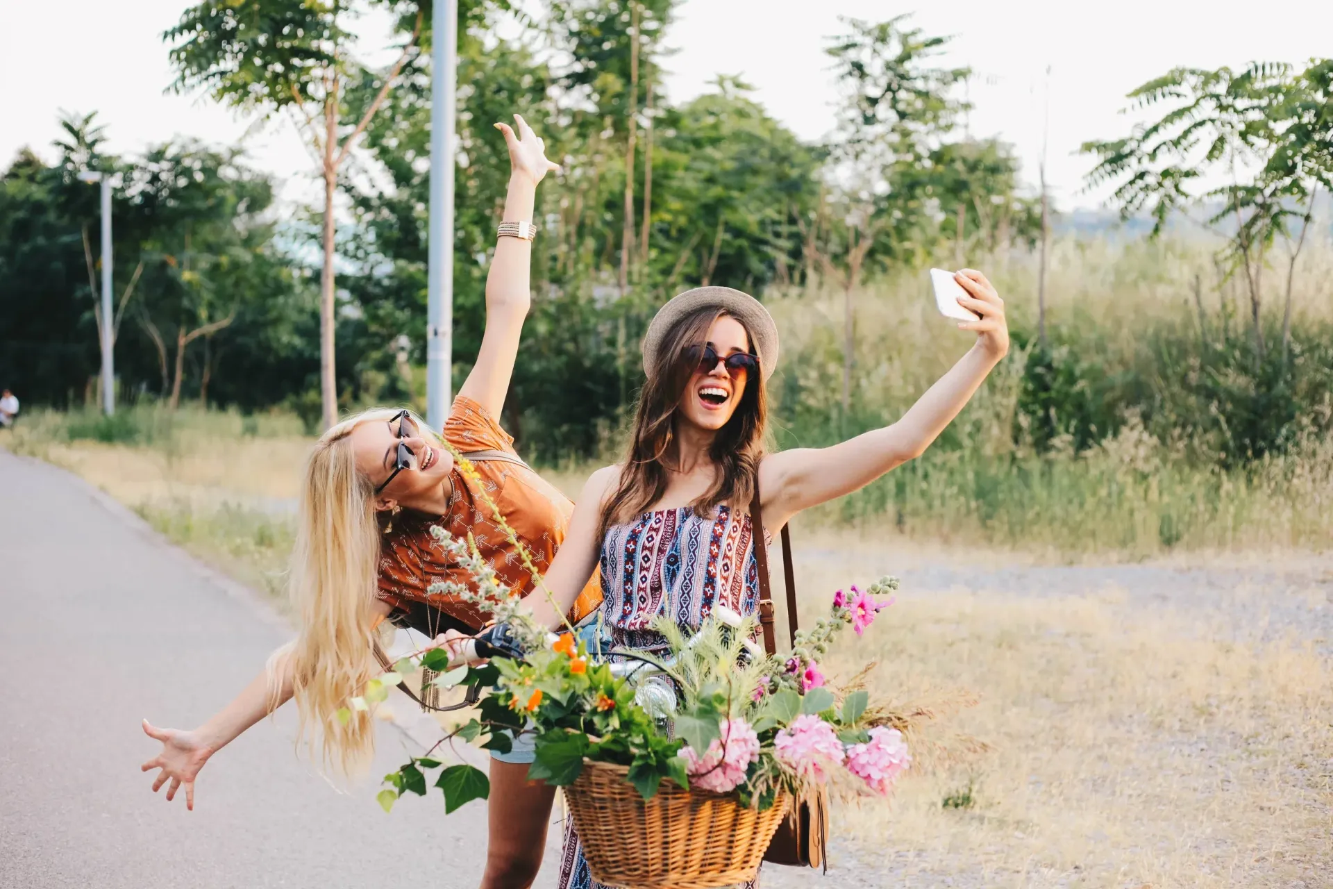 Two girls riding a bike with a basket of flowers.