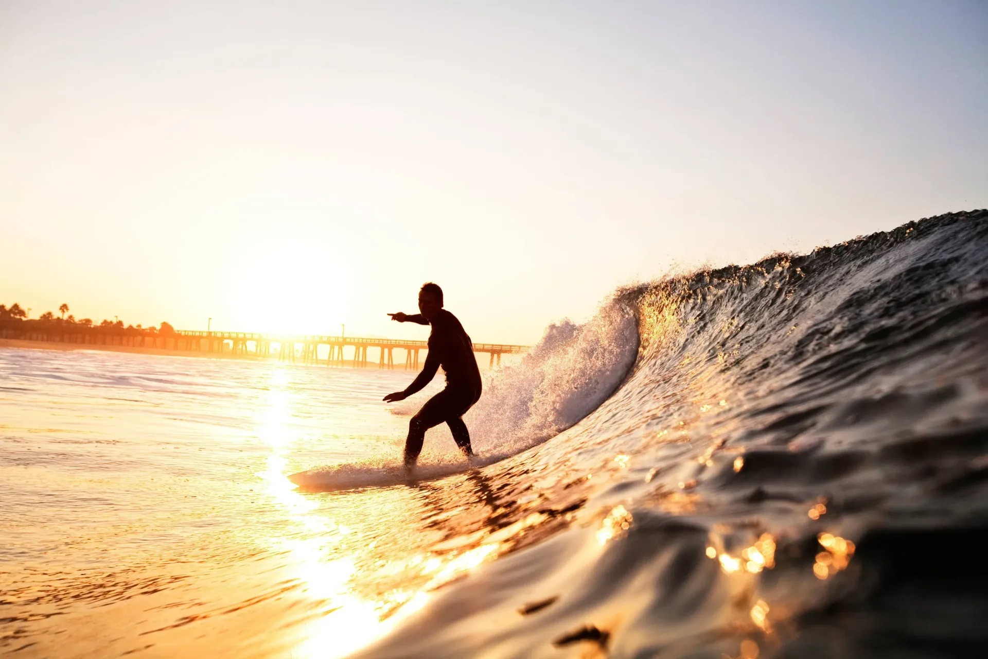 Surfer catching a good wave at sunset.