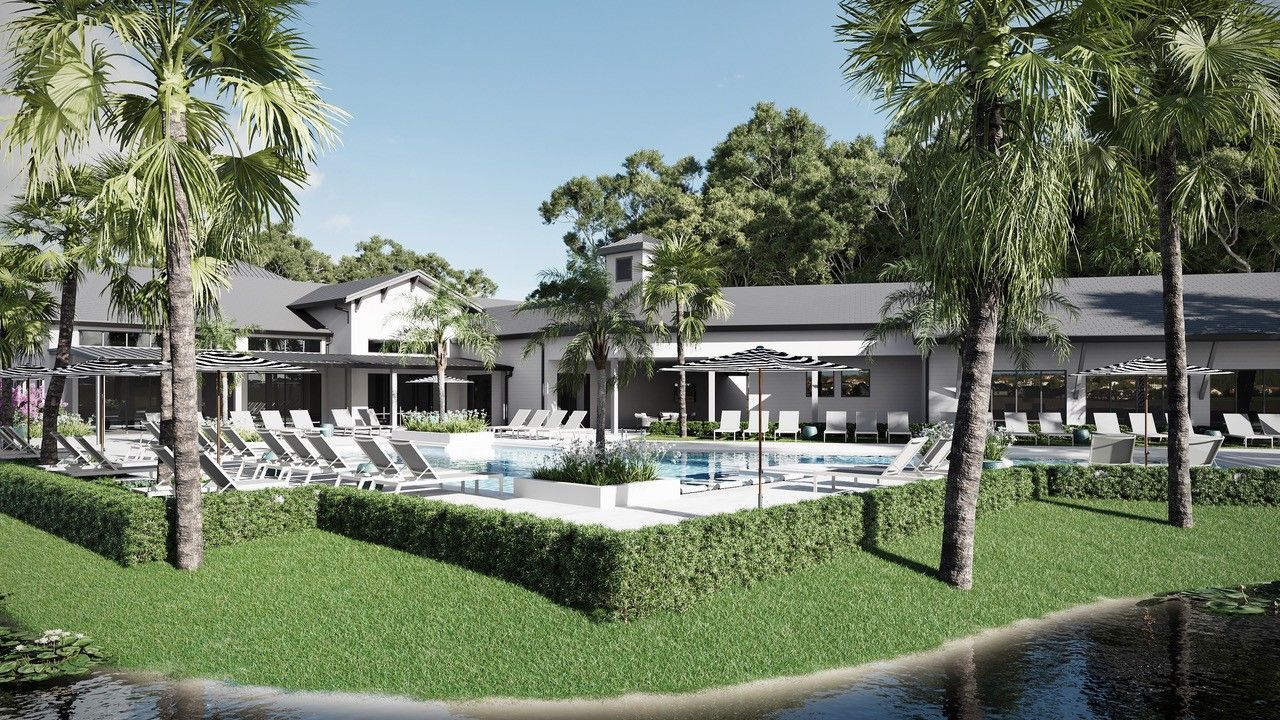 Resort pool with lounge chairs, palm trees, and white buildings beside a pond.