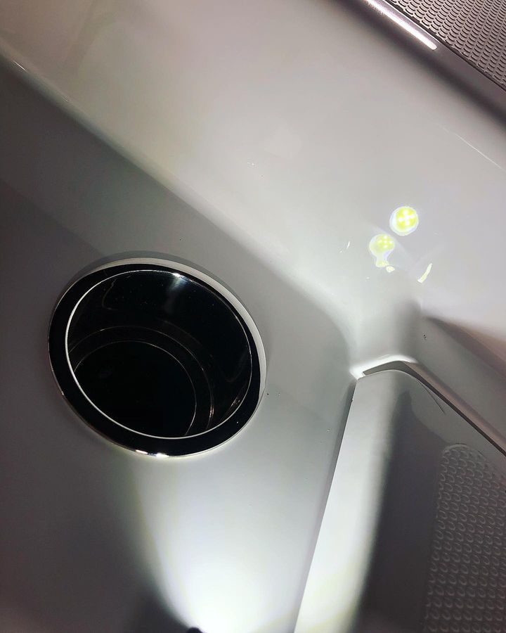 Cup holder in a white surface, with a shiny metallic rim.