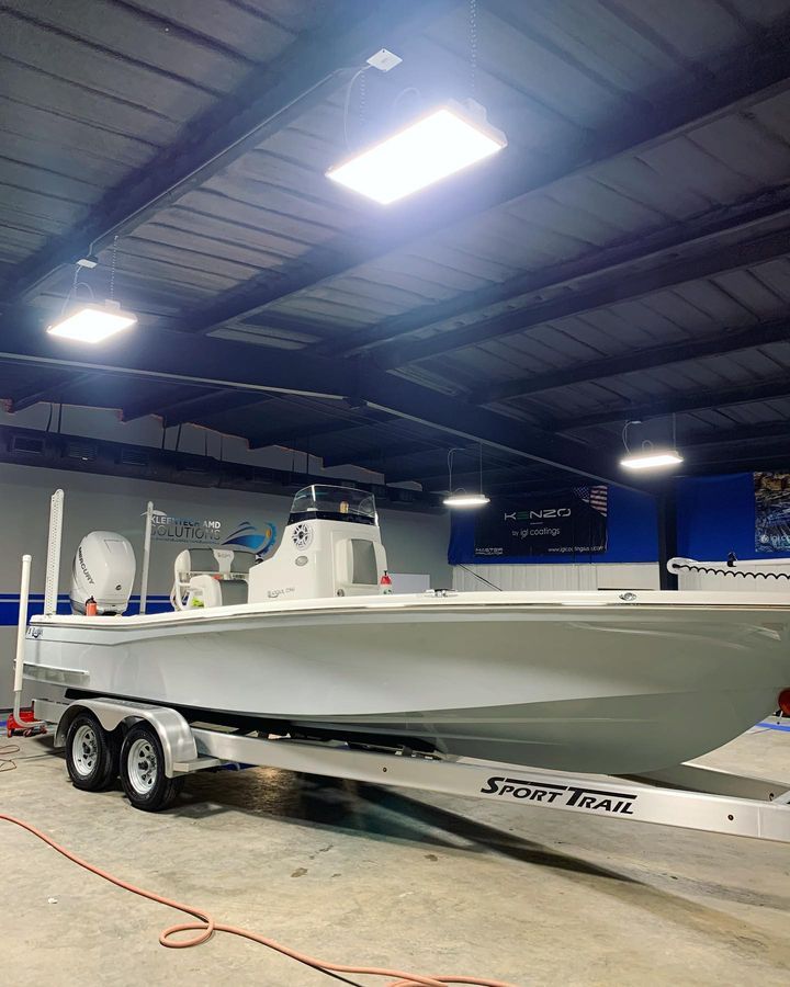 A white boat on a trailer inside a building with overhead lights.