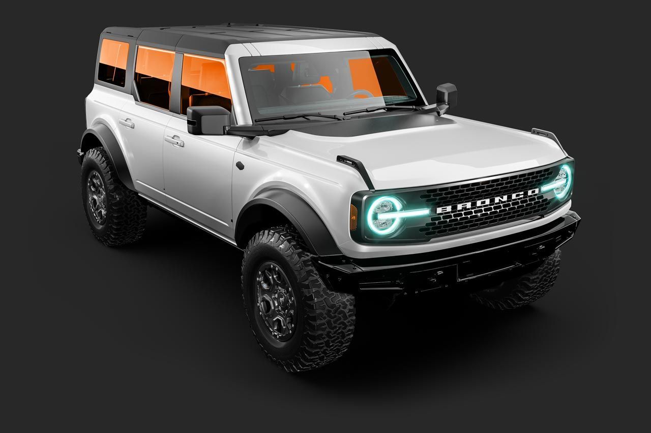 White Ford Bronco SUV on a dark surface with orange-tinted windows and glowing headlights.