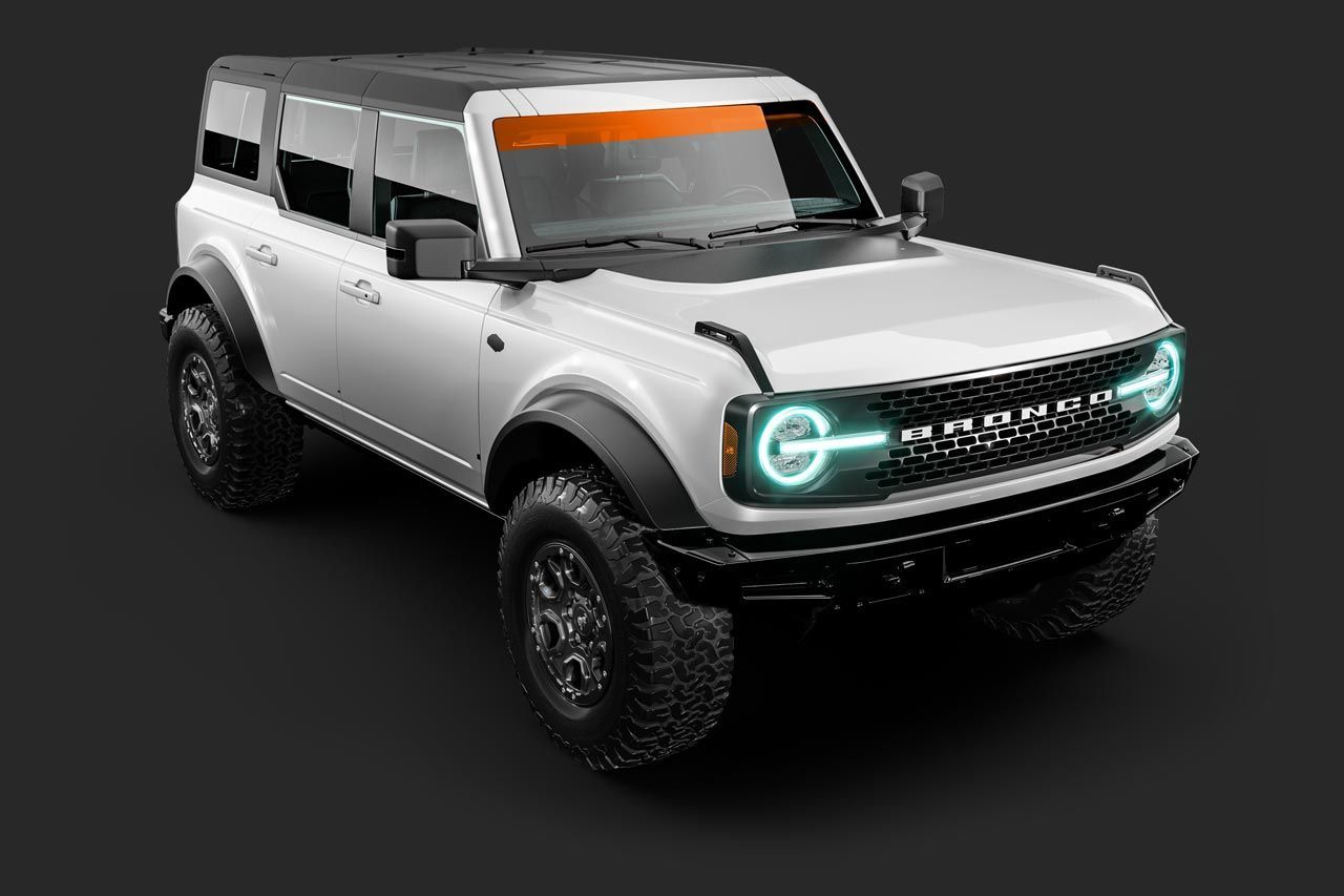 White Ford Bronco off-road vehicle with black accents, orange windshield banner, on a dark gray surface.