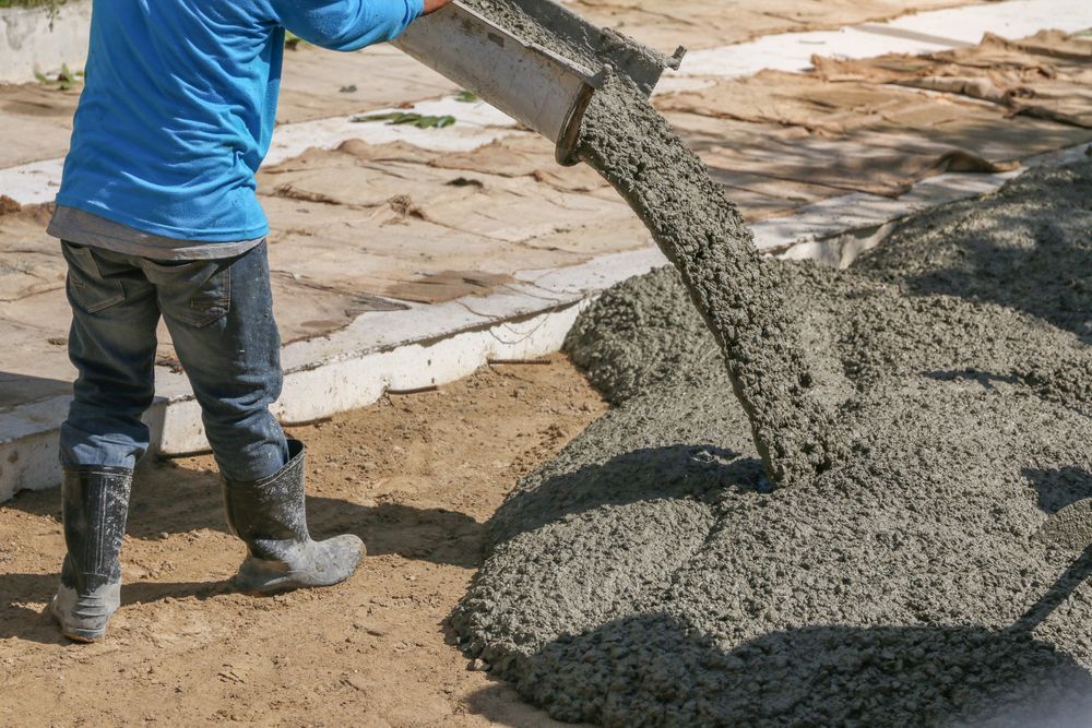Person in Blue Shirt and Jeans Pouring Concrete — Atherton Tableland Concreting in Herberton, QLD