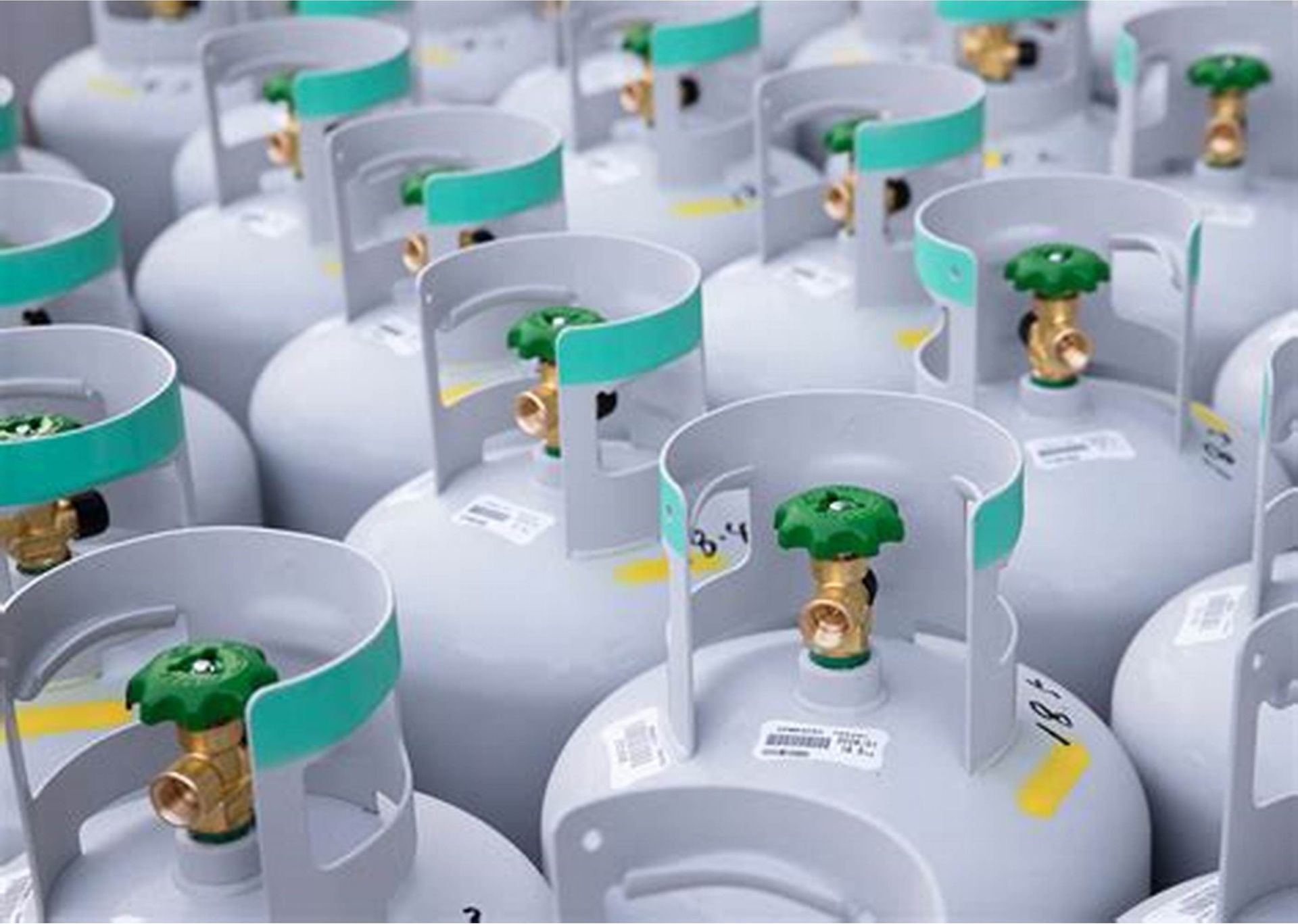 Een aantal gasflessen met groene ventielen staan op een rij.