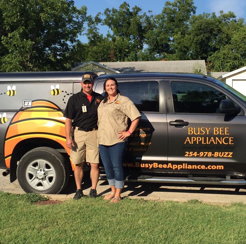 Two people standing in front of a busy bee appliance truck