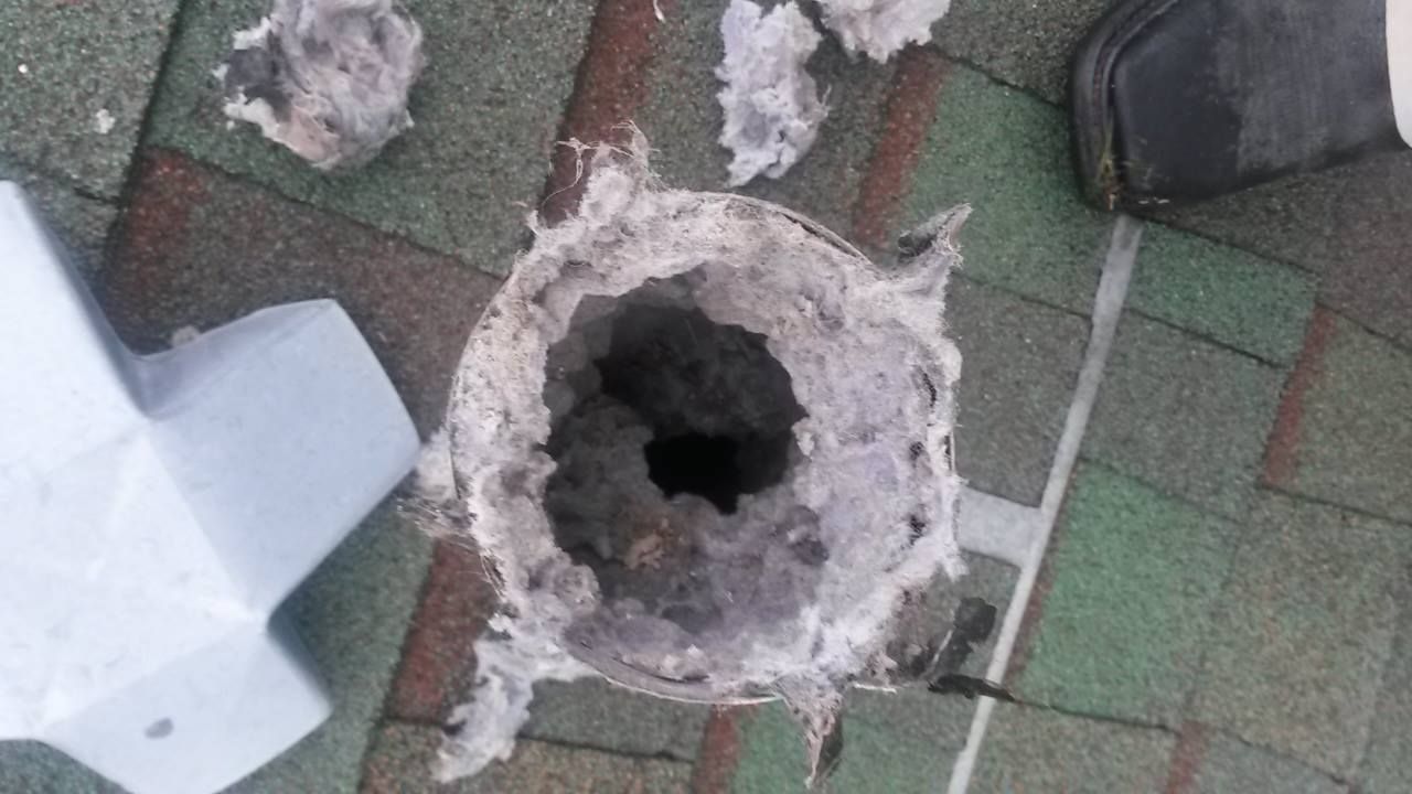 A hole in the roof of a house with a lot of dust coming out of it.