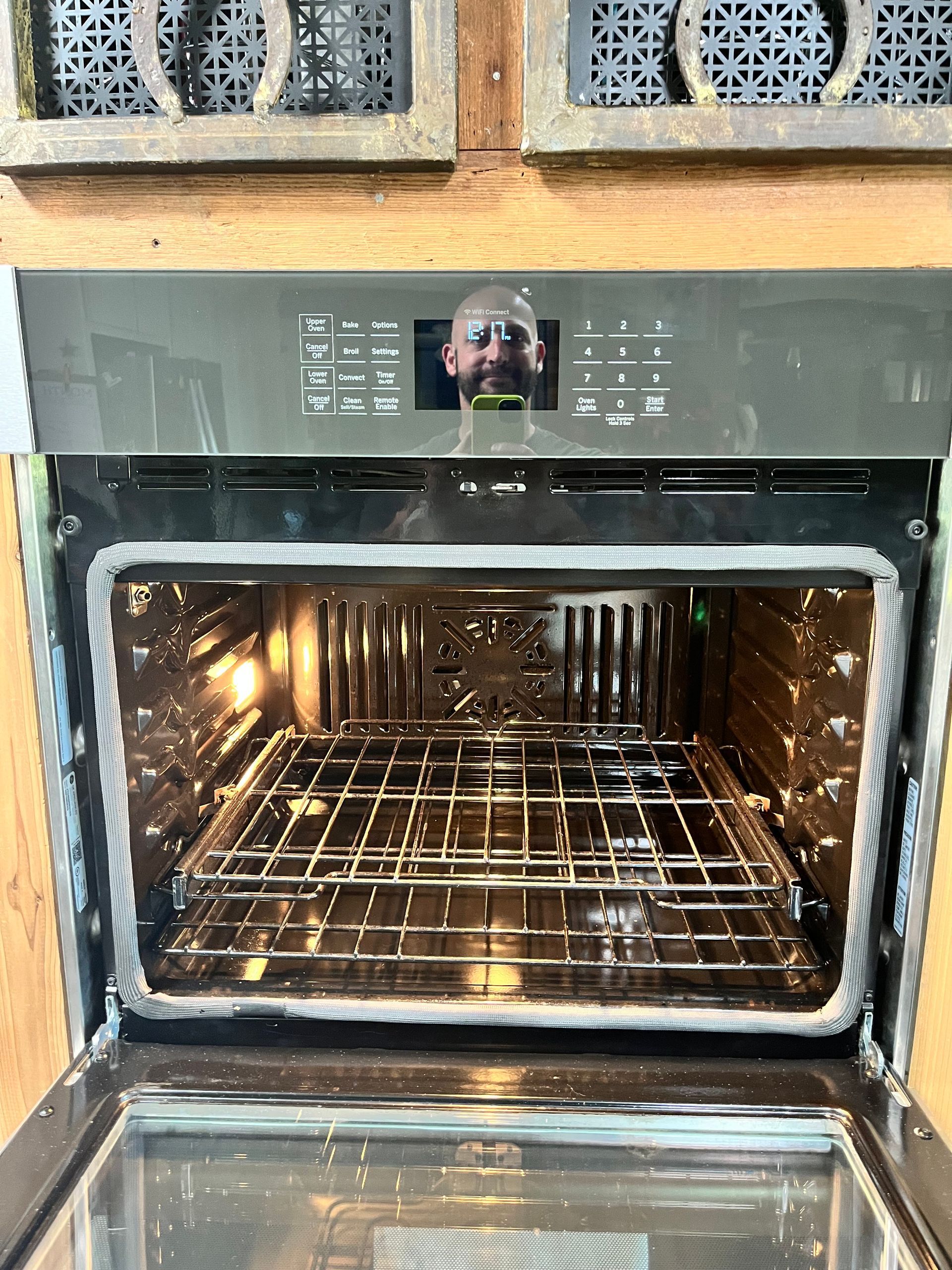 The inside of an oven with the door open and a picture of a man on the display.