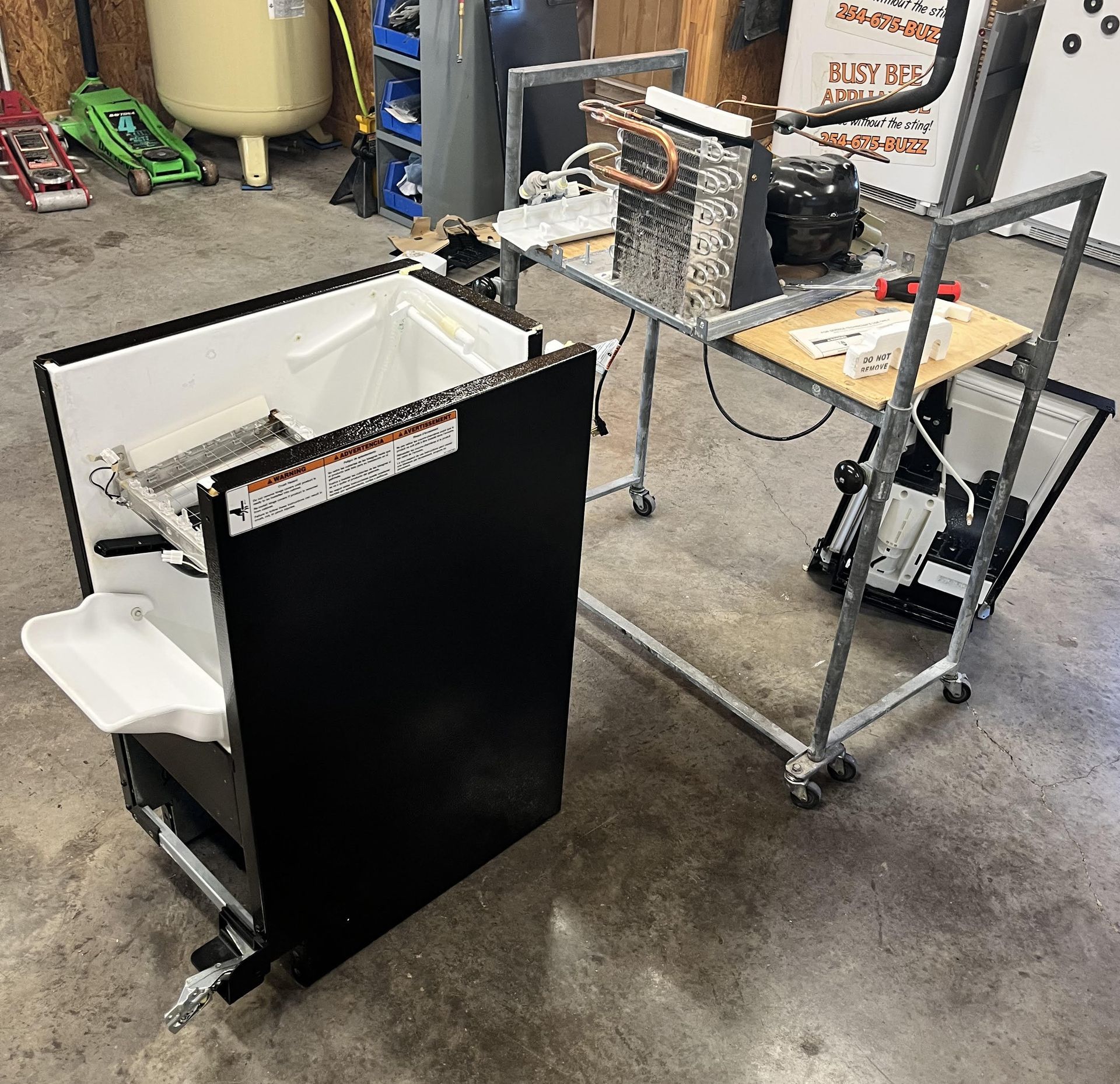 A refrigerator is being repaired in a garage.
