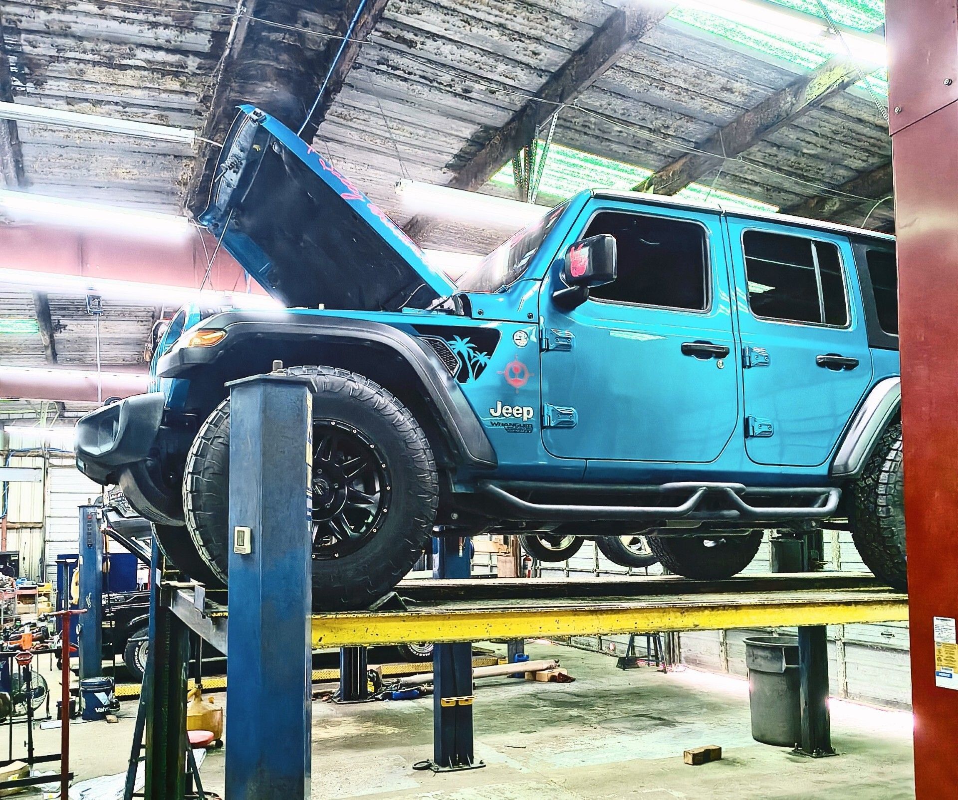 Mechanic inspecting a car’s underside on a lift in a bright auto repair shop