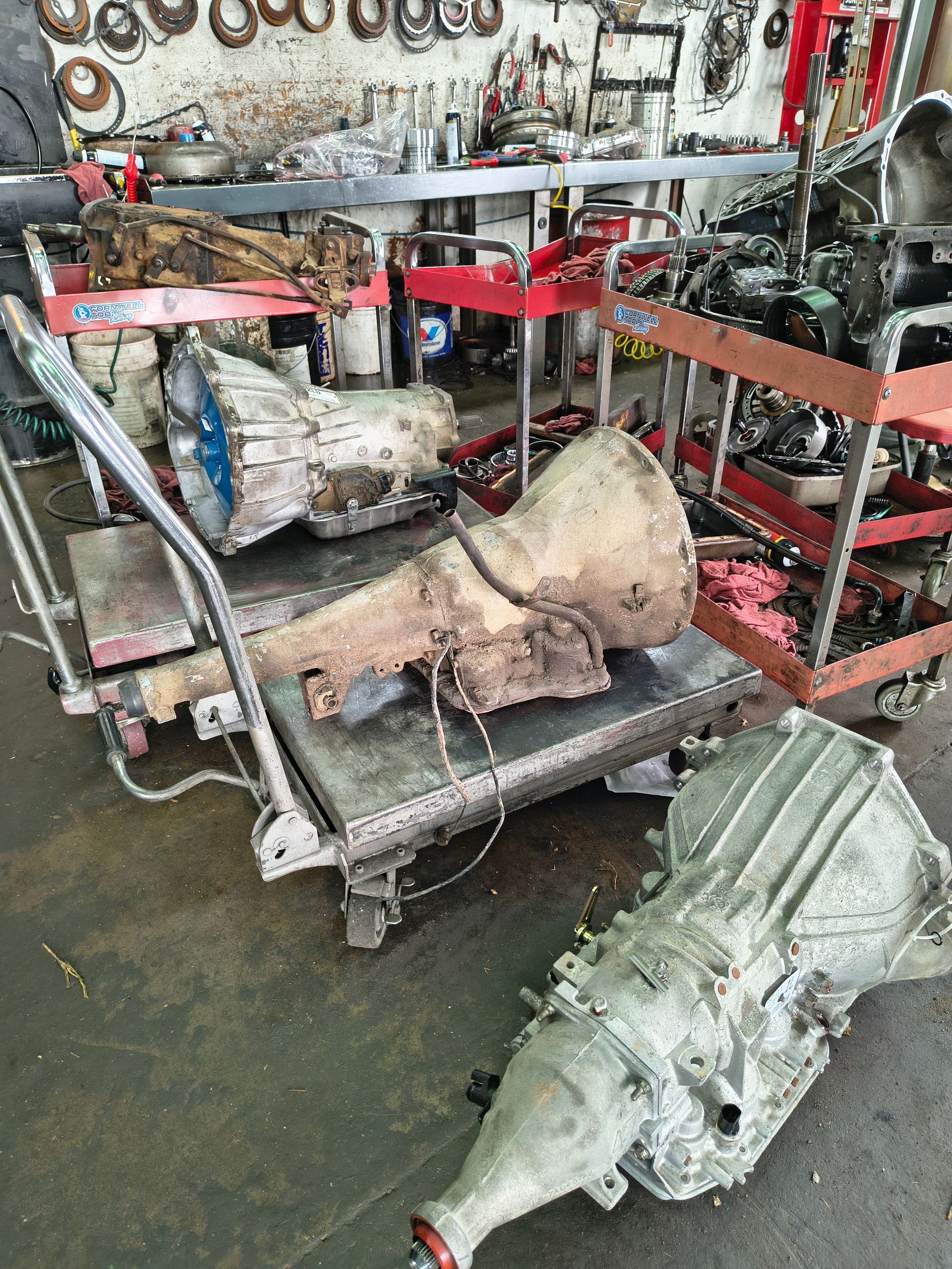 Mechanic repairing a vehicle transmission with tools, close-up of greasy engine parts.