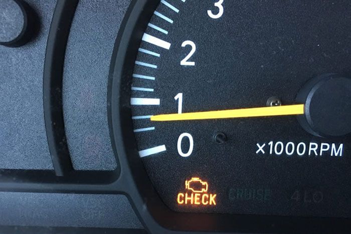 Close-up of a car tachometer near 1,000 RPM with the check engine light on.