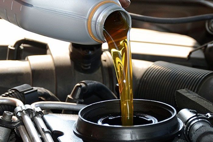 Motor oil being poured into a car engine from a silver container