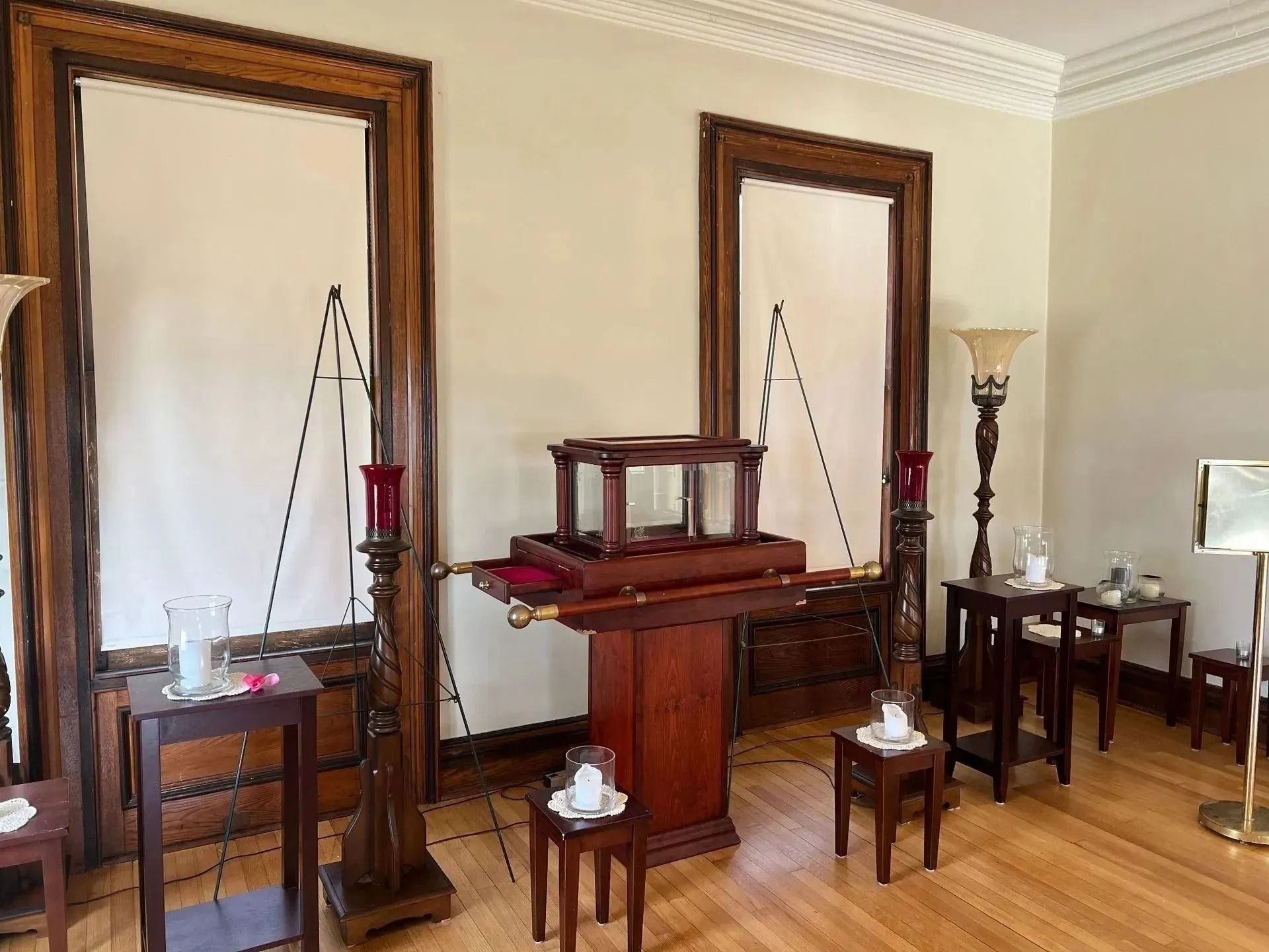 Interior with a wooden pulpit, two tall mirrors, chairs, and a side table in a formal room