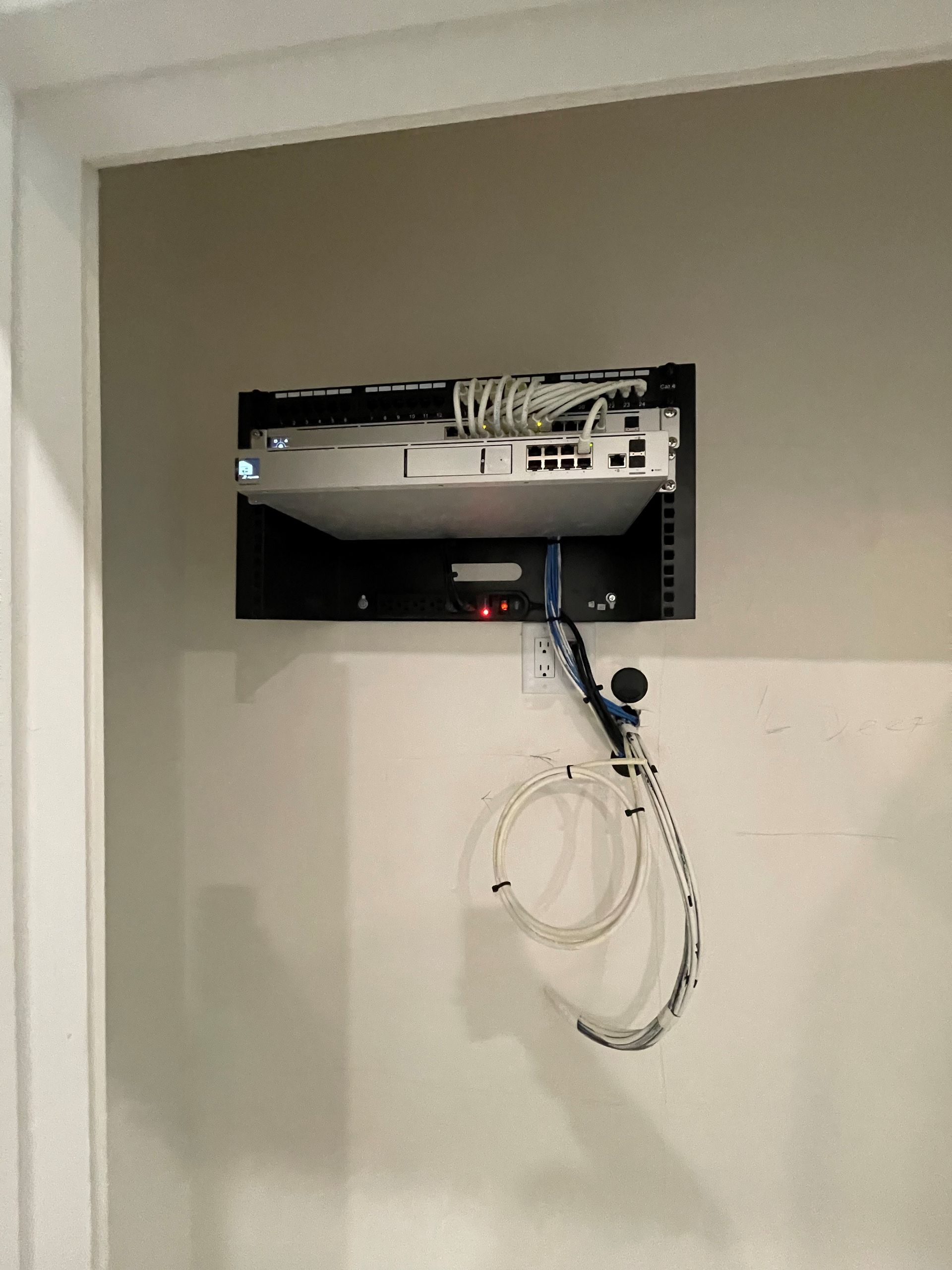 A projector is mounted on a wall with wires hanging from it.