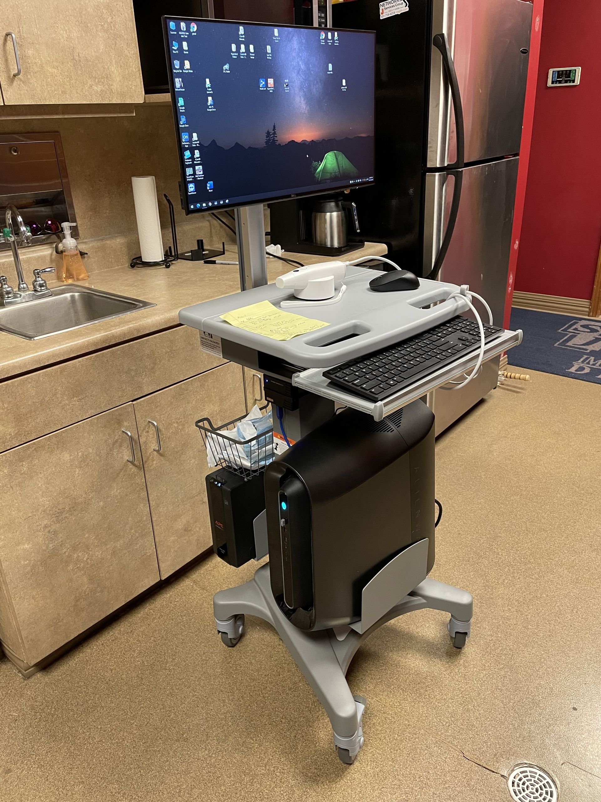 A computer is sitting on top of a cart in a kitchen.