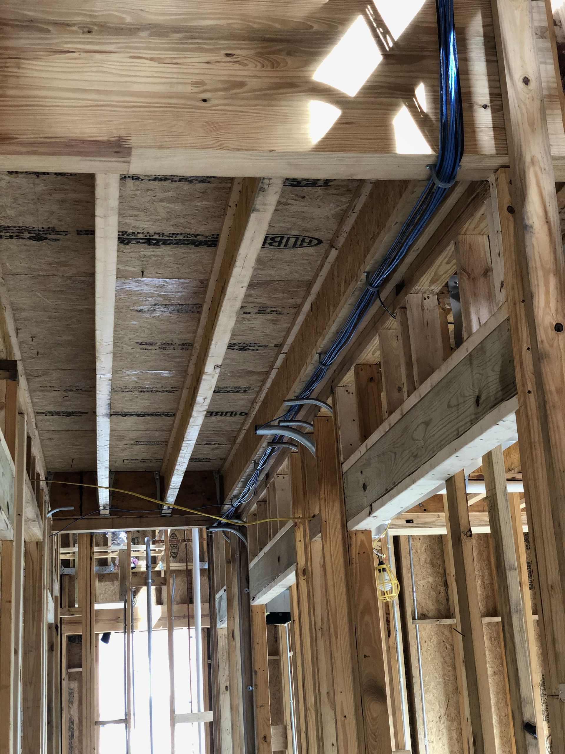 A building under construction with a lot of wooden beams and pipes hanging from the ceiling.