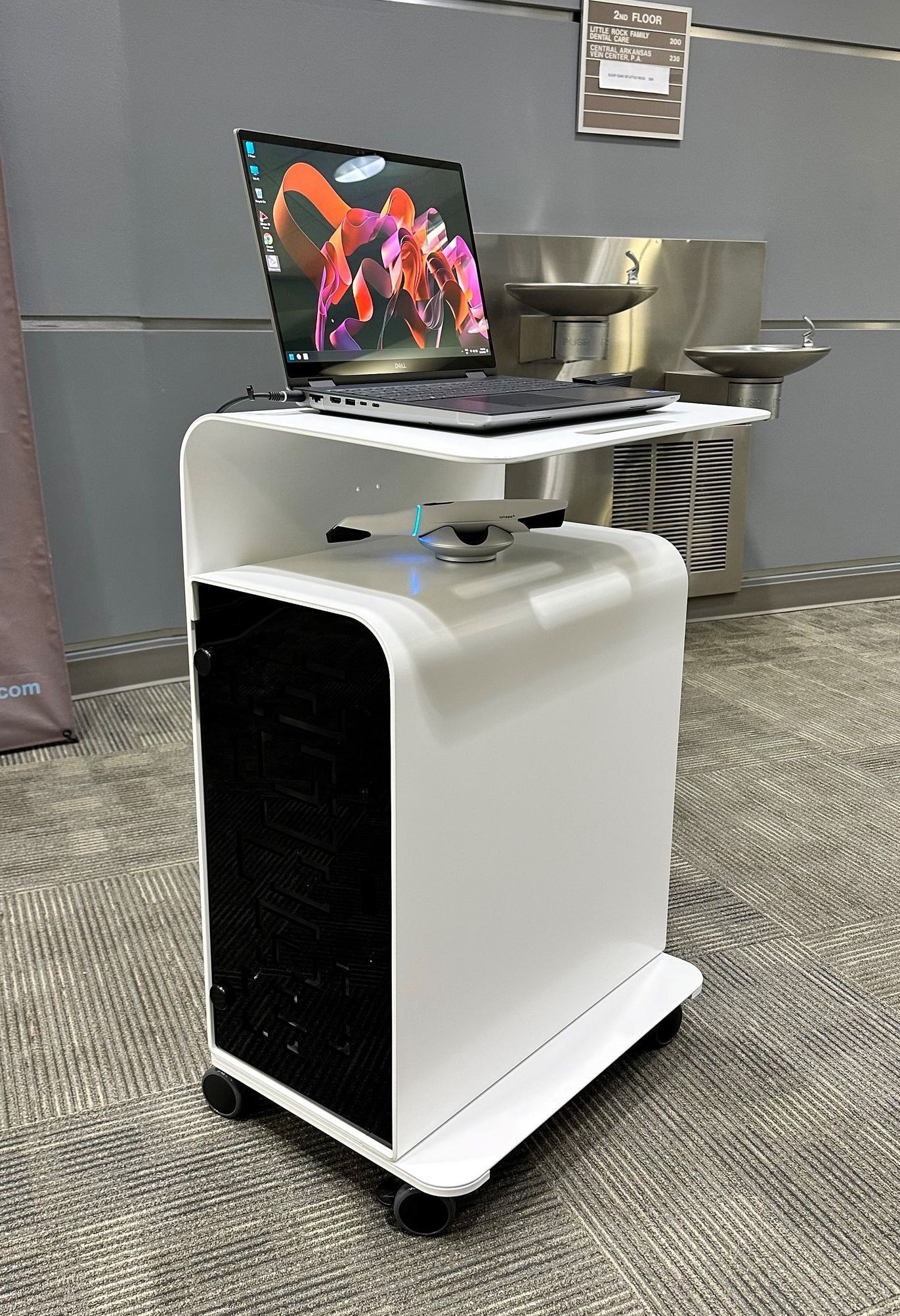 A computer is sitting on top of a cart in a kitchen.
