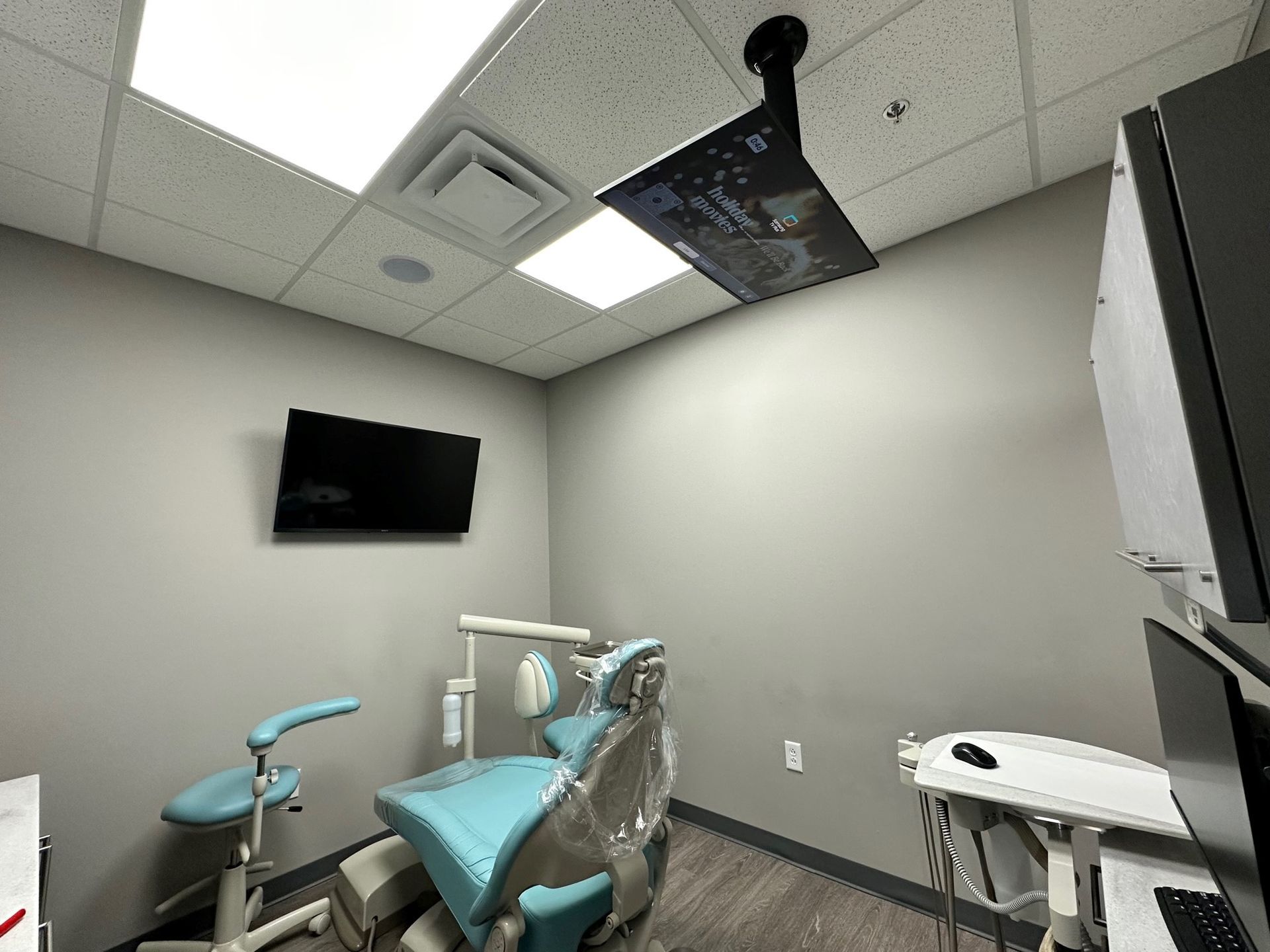 A dental office with a dental chair and a television on the wall.
