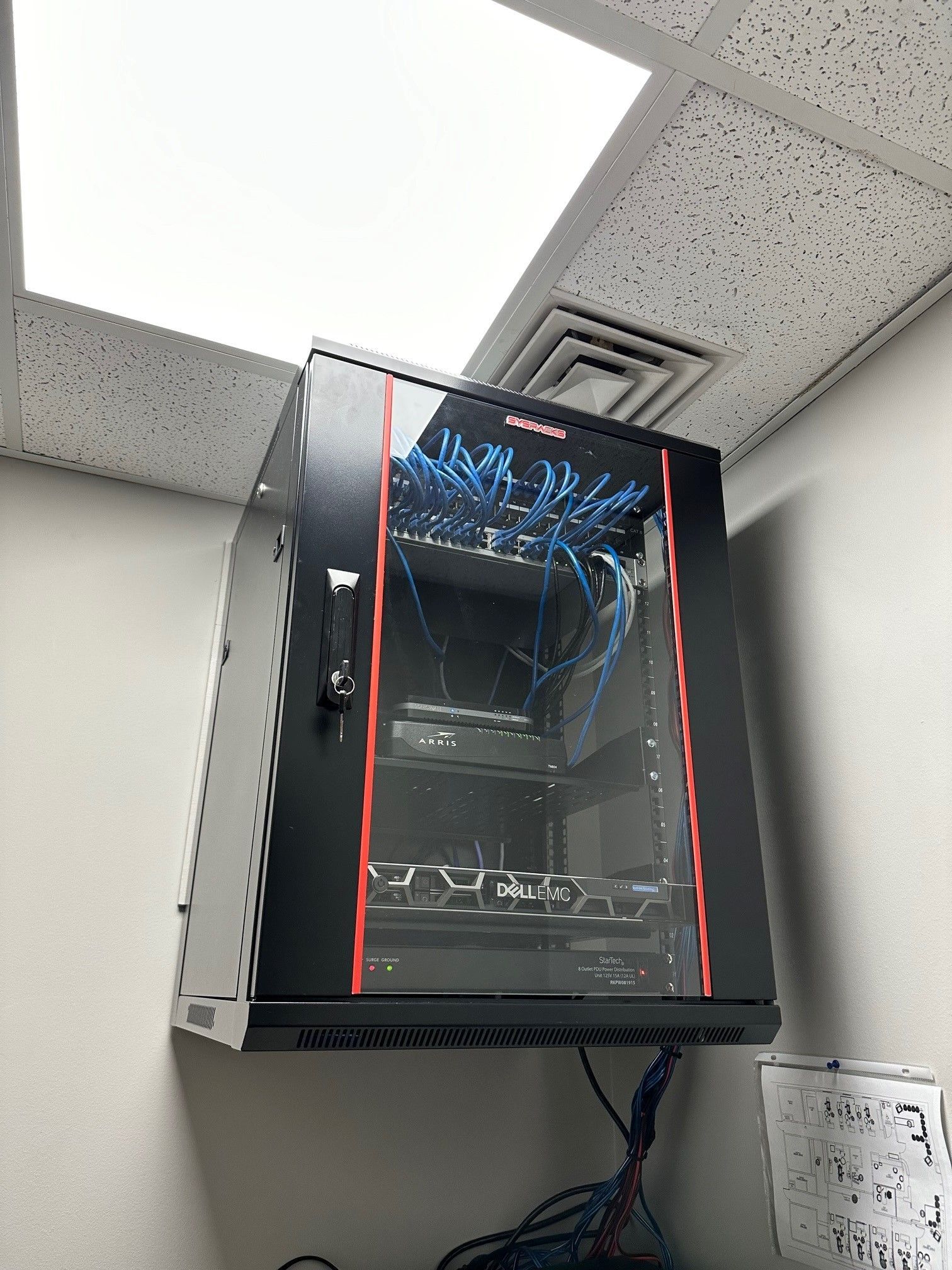 A server cabinet is hanging from the ceiling in a room.