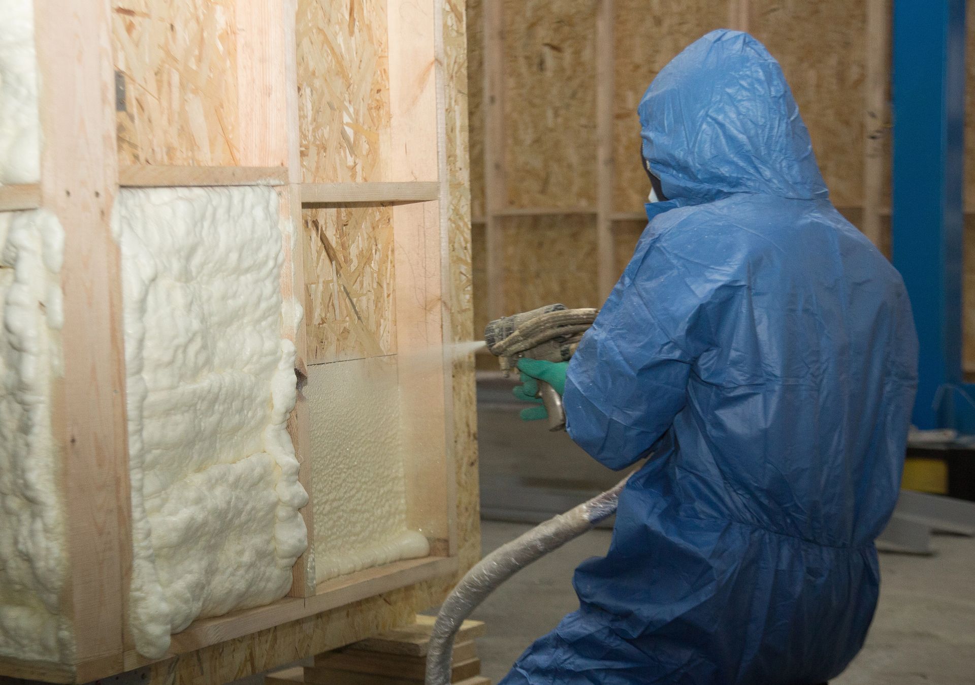 Local insulation specialist spraying spray foam insulation on a wall to improve energy efficiency.