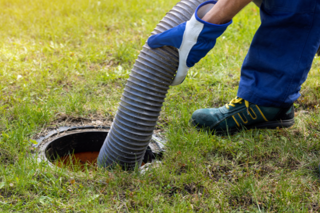 Johnny Jones Plumbing - A person is pumping a hose into a septic tank.