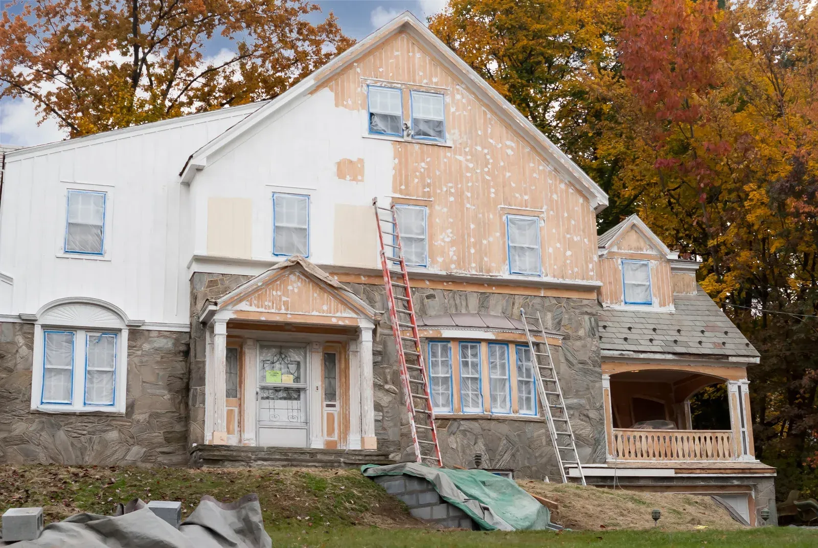 A house is being remodeled with a ladder in front of it.