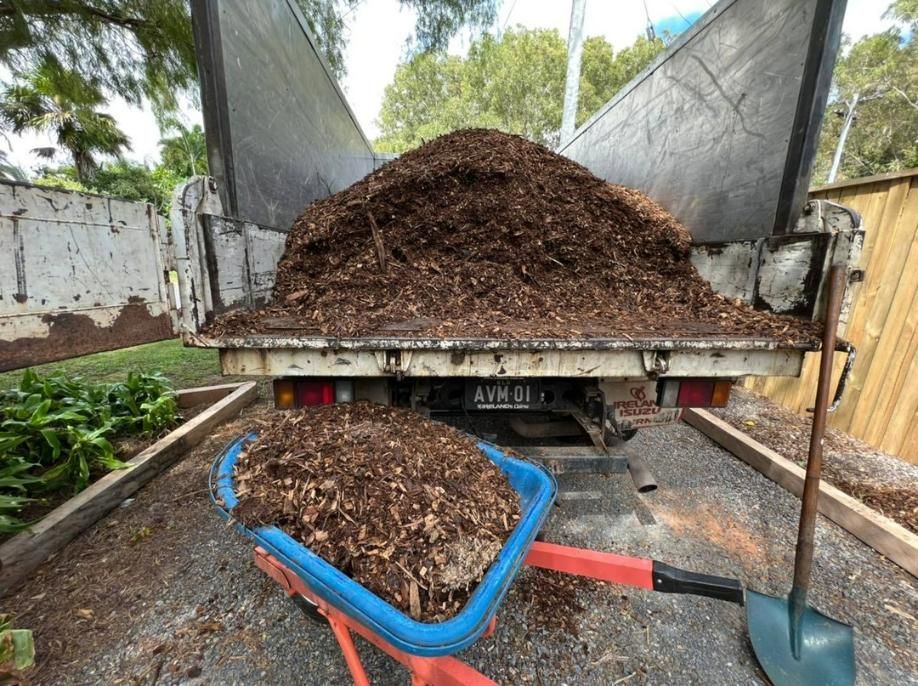 A Wheelbarrow Is Sitting in Front of A Truck Filled with Mulch — Advanced Vegetation Management in Cairns City, QLD