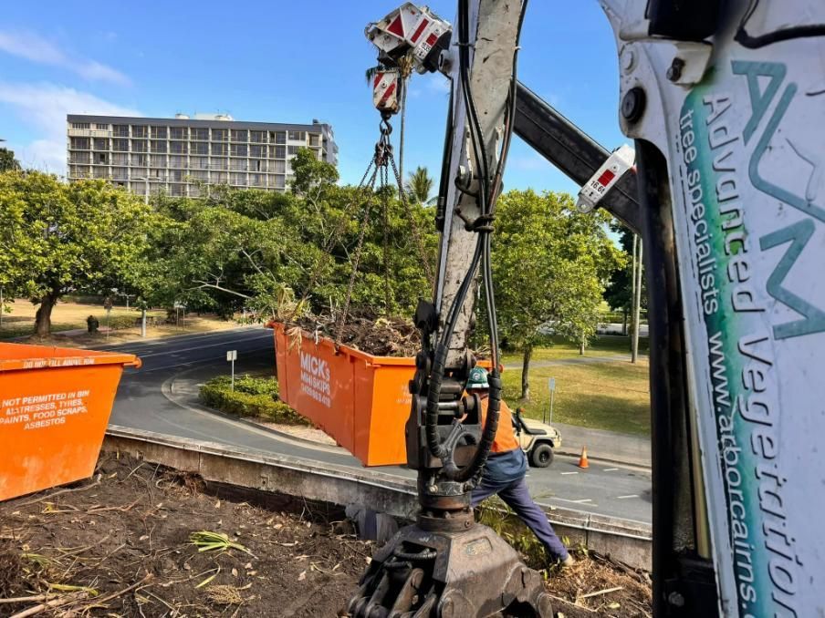 A Large Orange Dumpster Is Being Lifted by A Large Excavator — Advanced Vegetation Management in Stratford, QLD