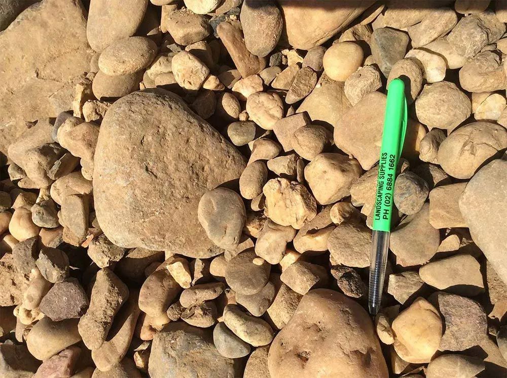 Green Pen Laying on Stones — Dubbo Soils & Landscaping Supplies in Dubbo, NSW