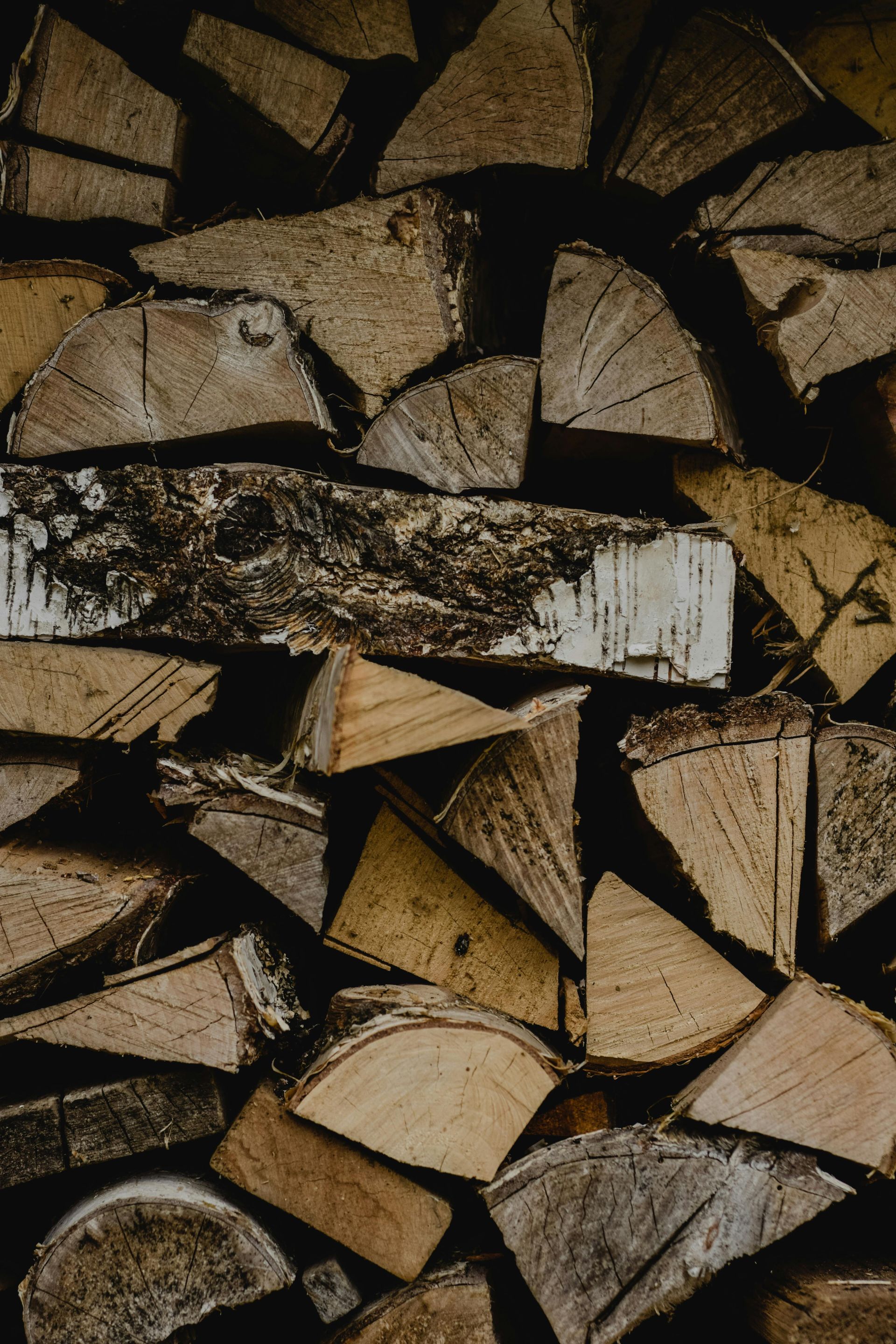 A Man Moving the Pile of Stacked Firewood — Dubbo Soils & Landscaping Supplies in Dubbo, NSW