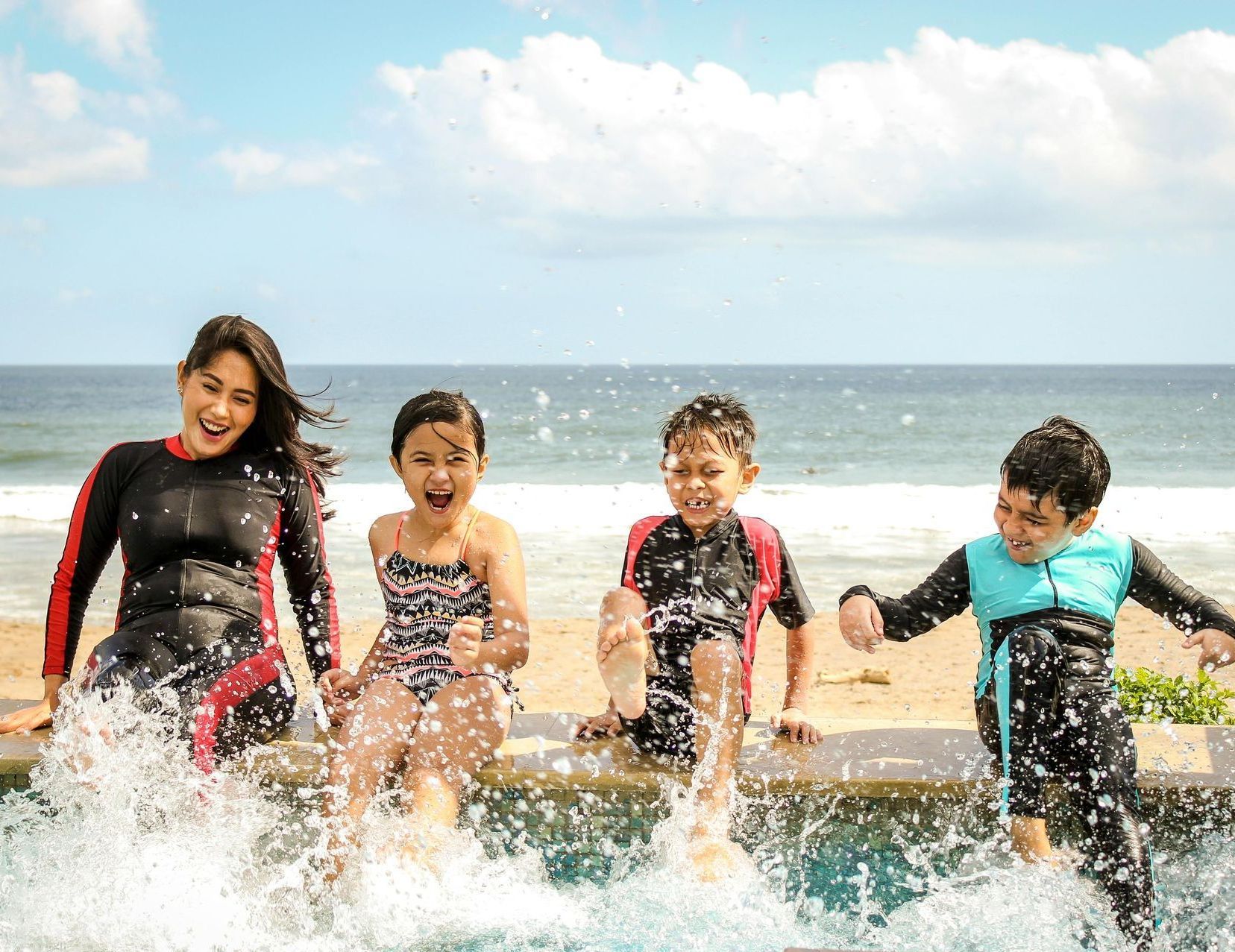 A group of children are splashing in a pool on the beach.