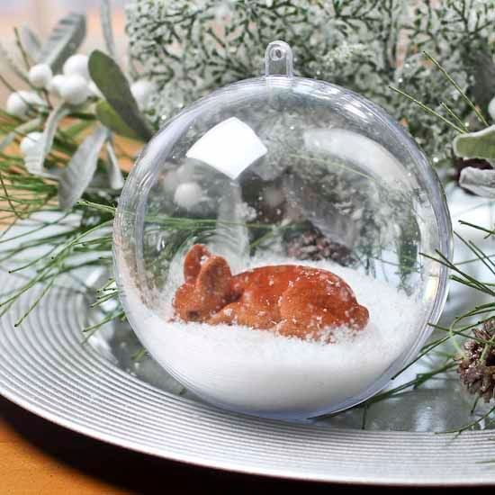 Ein Weihnachtsornament mit einem Hirsch darin auf einem Teller.