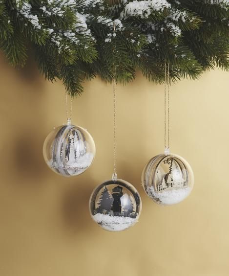 Drei Weihnachtsdekorationen hängen an einem Weihnachtsbaumzweig.