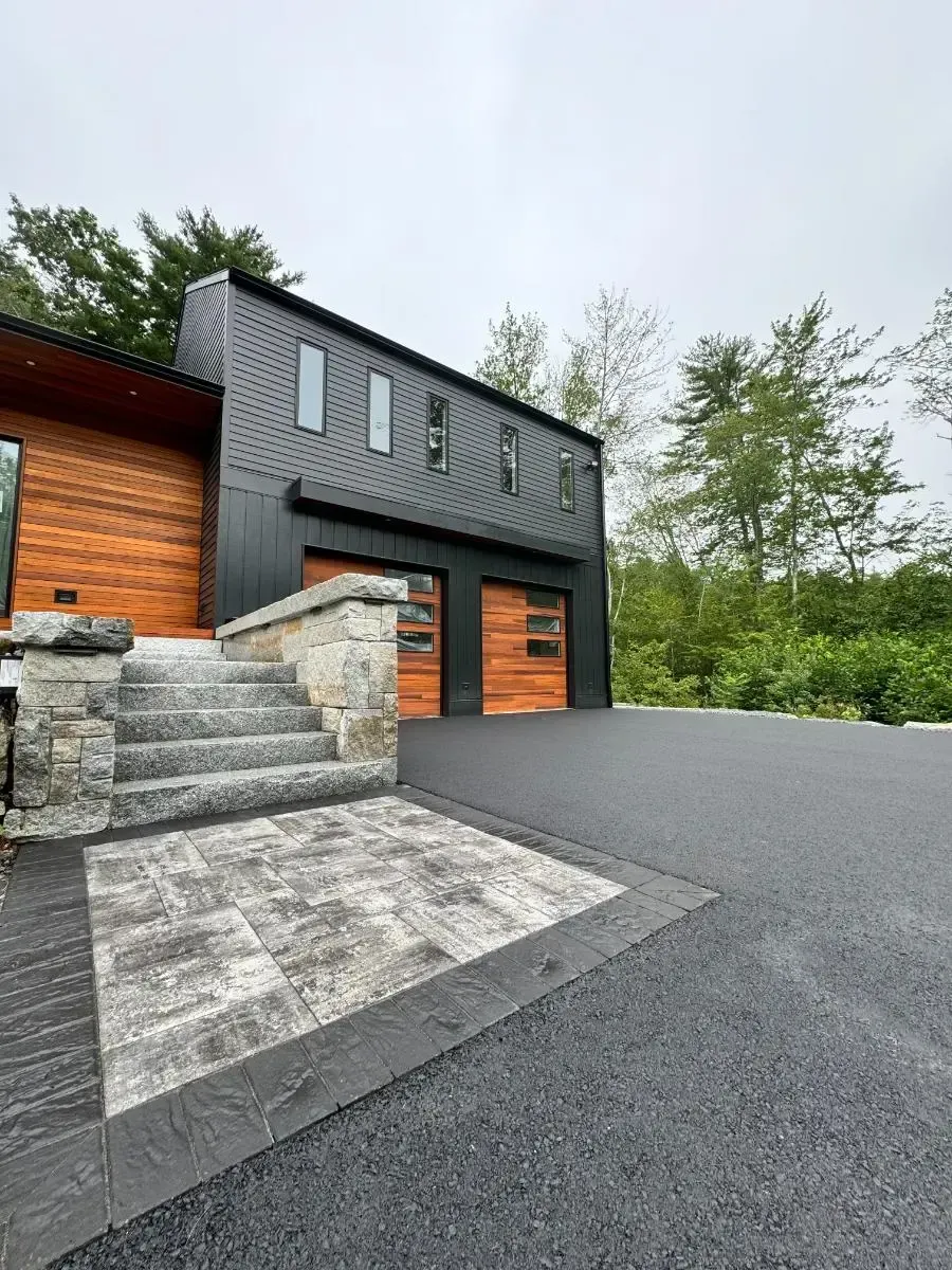 Modern house with a black exterior, wooden accents, and a stone walkway.