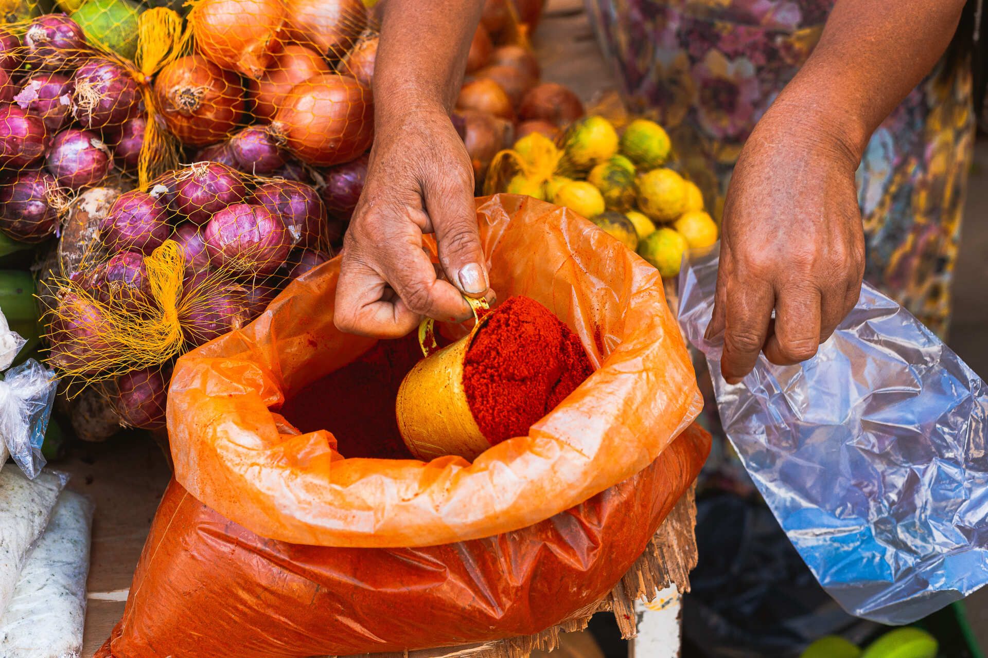 Uma mulher está segurando um saco de pimenta vermelha em pó.