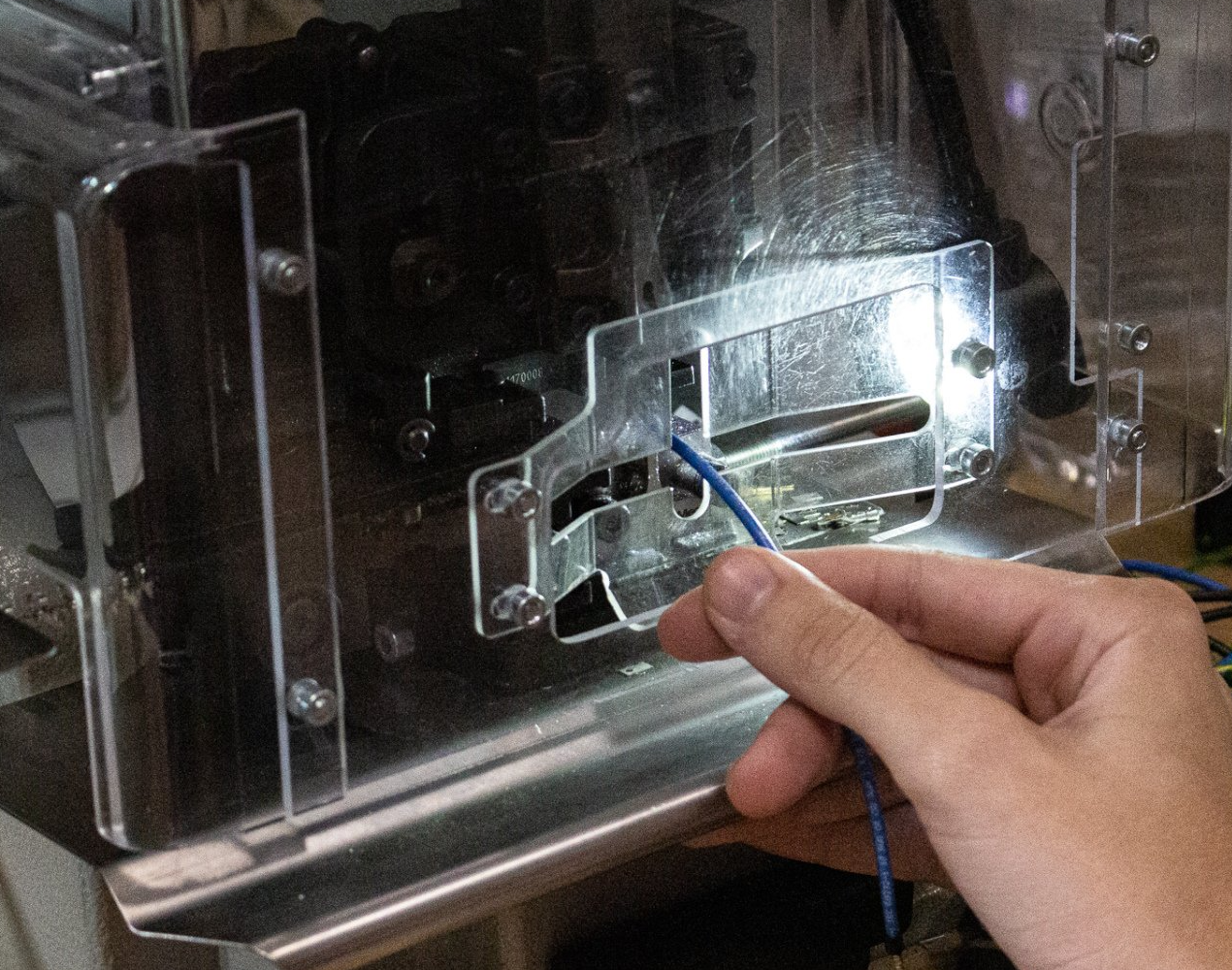 A person is holding a wire in front of a machine